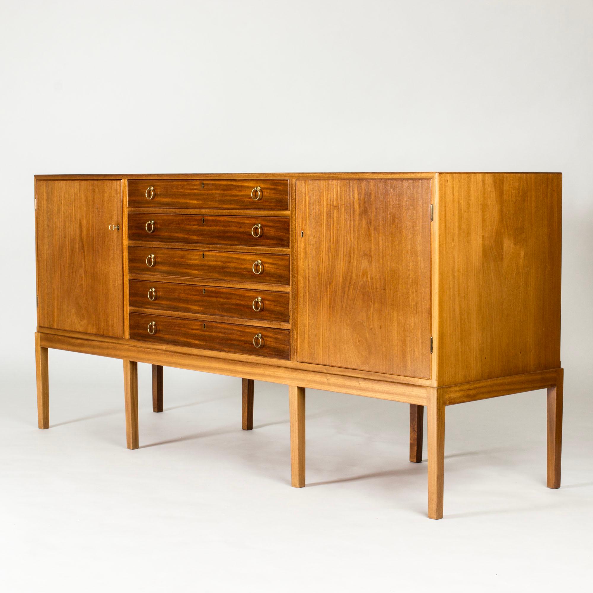 Grande credenza del designer ed ebanista Jacob Kjær, realizzata in mogano con maniglie decorative in ottone. Tutti i cassetti contengono portautensili in feltro per organizzare le posate.