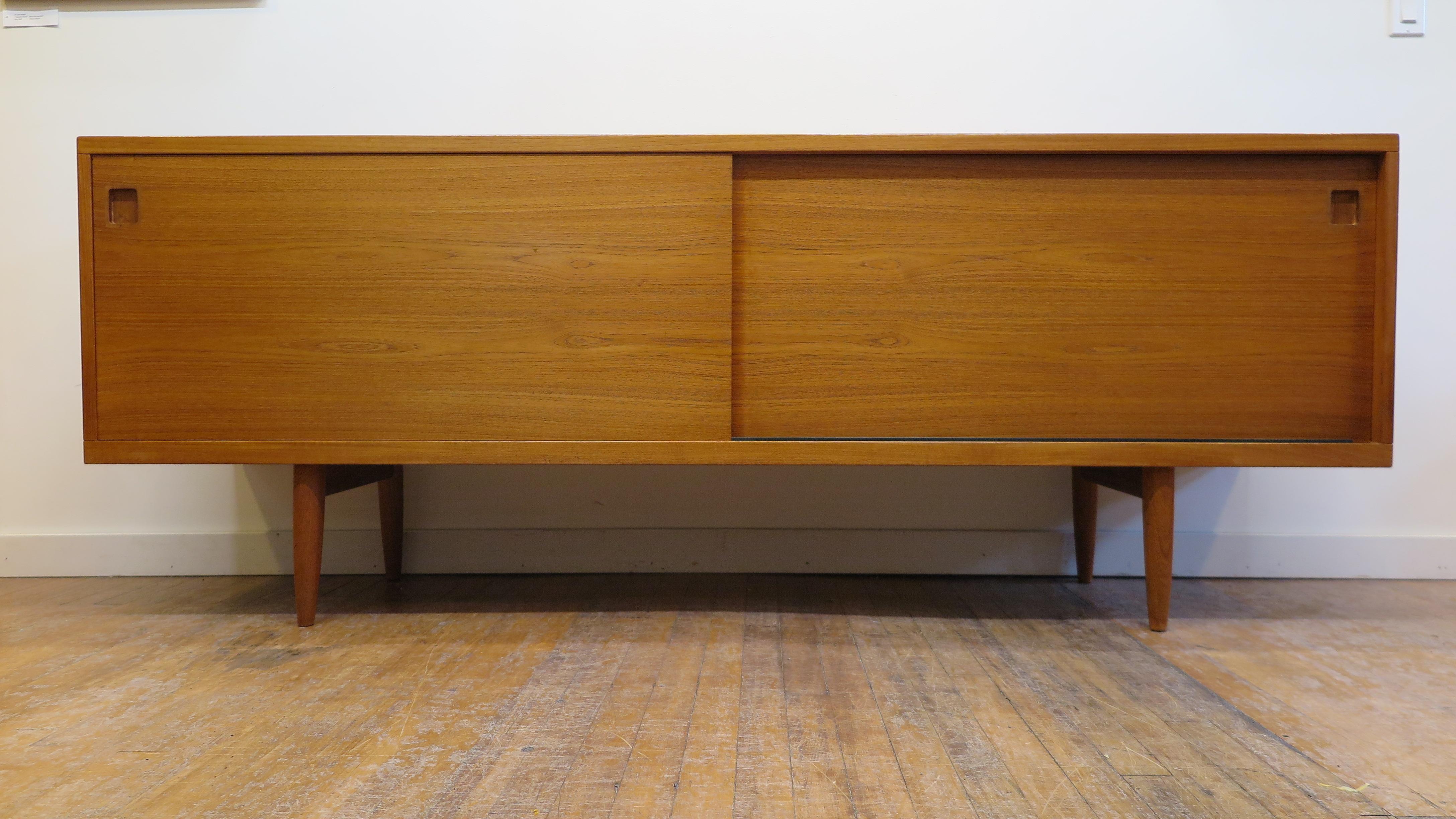 Niels Otto Moller Danish modern sideboard model 20 in teak. An exceptional example of Danish modern furniture and design. Two sliding doors open to adjustable shelfs with four sliding drawer style shelfs. Minimal simple clean functional timeless