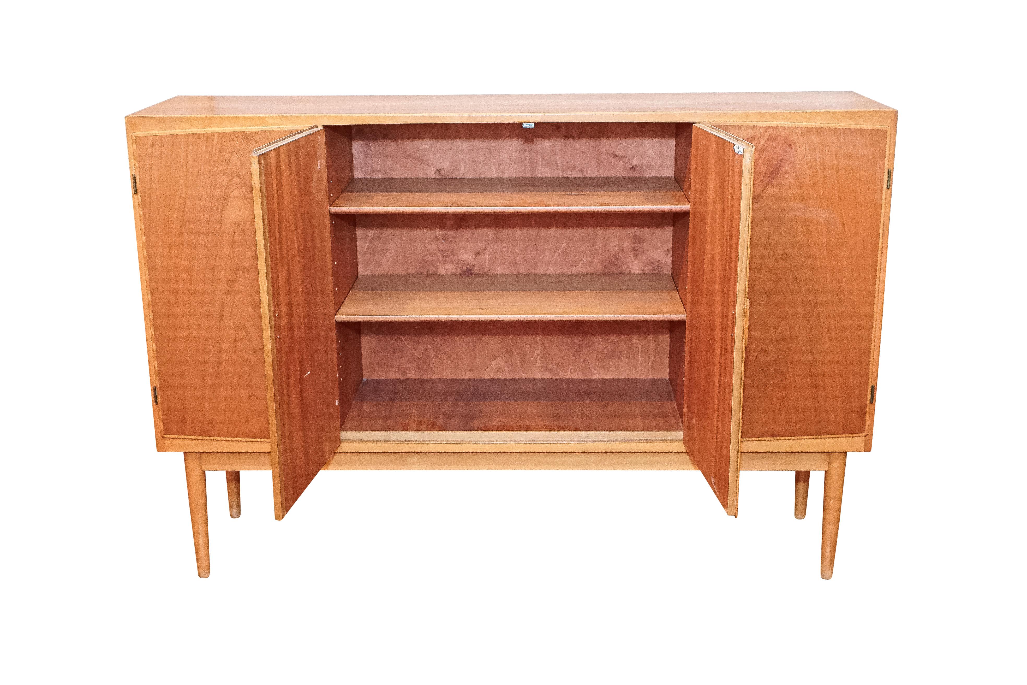 This fine example of Danish modern design is the work of the renowned cabinetmaker Poul Jeppesen, and is part of the heralded Rungstedlund series of the early 1950s. Interior shelves are adjustable and eight interior drawers are of varying size for