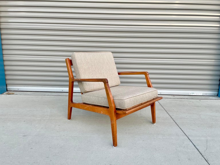 Danish modern single walnut lounge chair by Ib Kofod-Larsen for Selig in Denmark, circa 1960s. This vintage lounge chair features a solid walnut frame with angled legs and a sculpted slatted backrest to provide comfort and an excellent modern