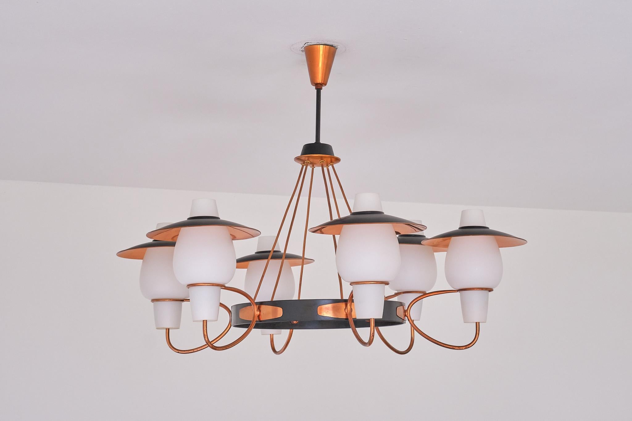 This striking six arm chandelier was produced in Denmark in the 1960s.

The fixture consists of six white opal glass shades, each with a separate reflective shade in copper mounted on top of the glass shade. This created a beautiful effect when