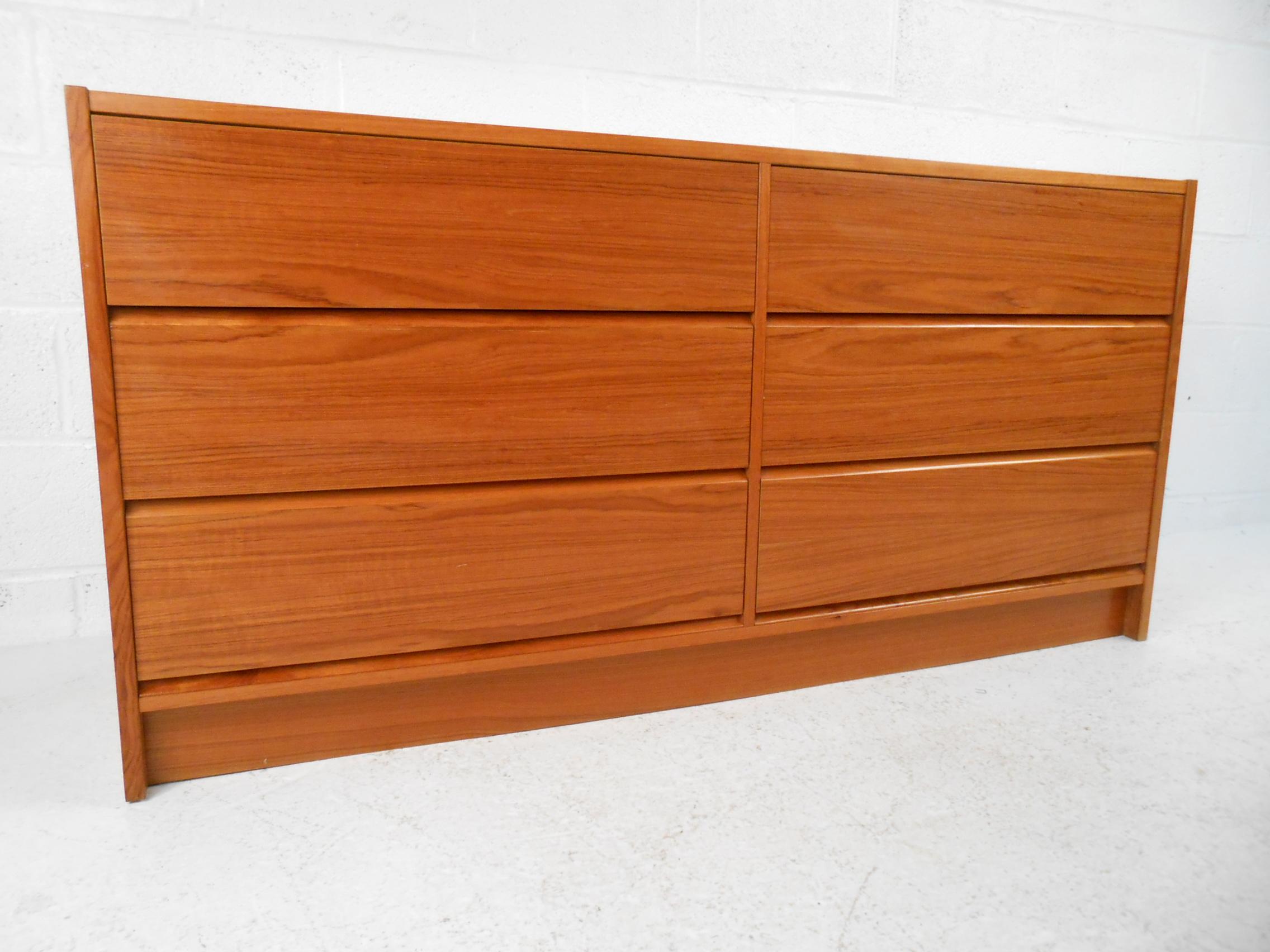 Handsome Danish modern six-drawer dresser. Teak veneer exterior with a nice color and grain pattern. Six spacious drawers with concealed pulls underneath the drawer-fronts. Simple and striking visual profile complimented by a skirt base. This Danish