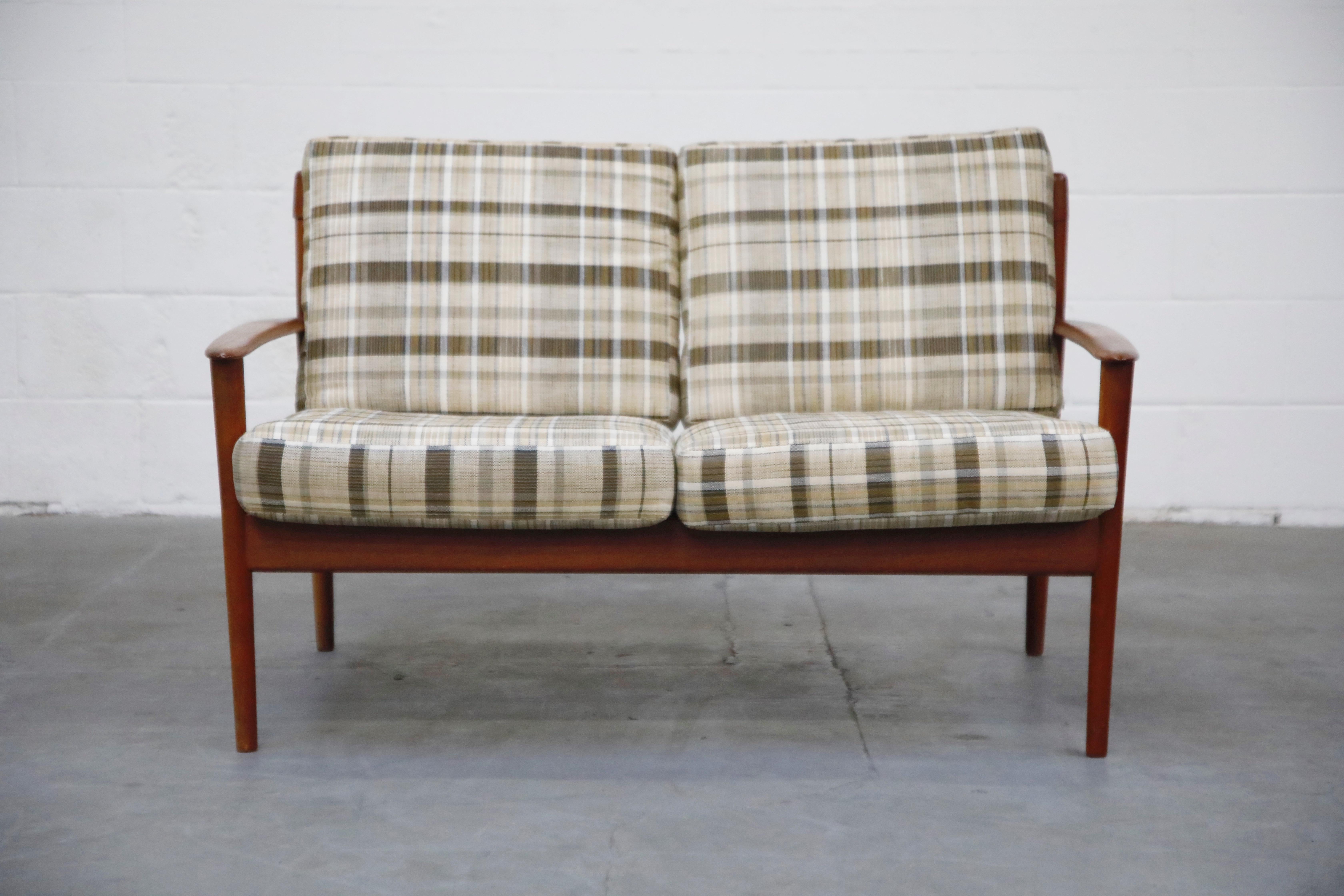 This lovely circa 1960 Danish modern teak settee is attributed to Folke Ohlsson for DUX, and shares similar styling to Hans Wegner's Cigar sofa and designs by Arne Vodder. The deep teak tones and sculpted arms and slatted wood back makes this an