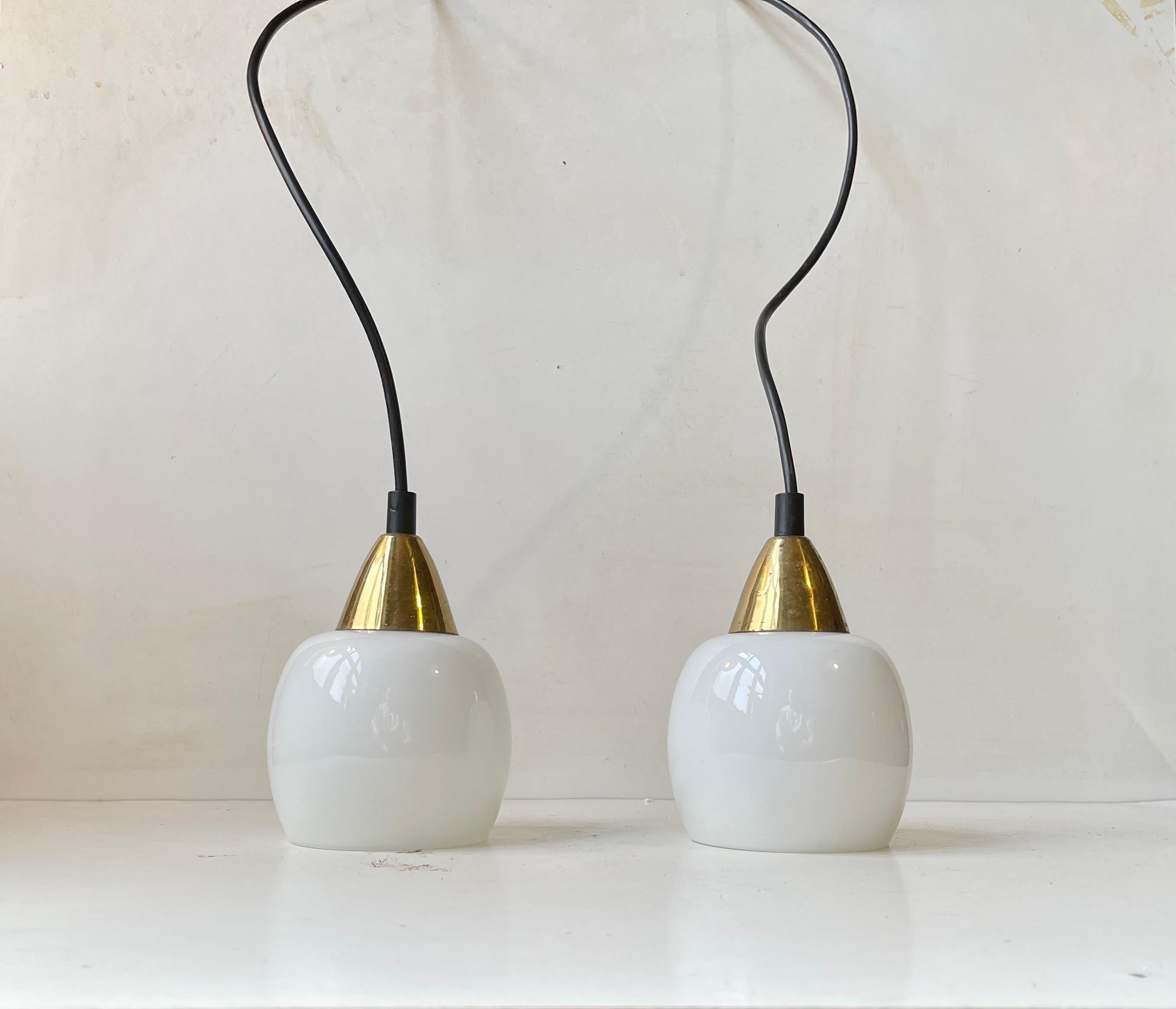 A set of window pendant lights composed of white opaline glass and brass. Manufactured in Denmark circa 1970 in a style reminiscent of Vilhelm Lauritzen. Measurements: H: 16 cm, Diameter: 10 cm.