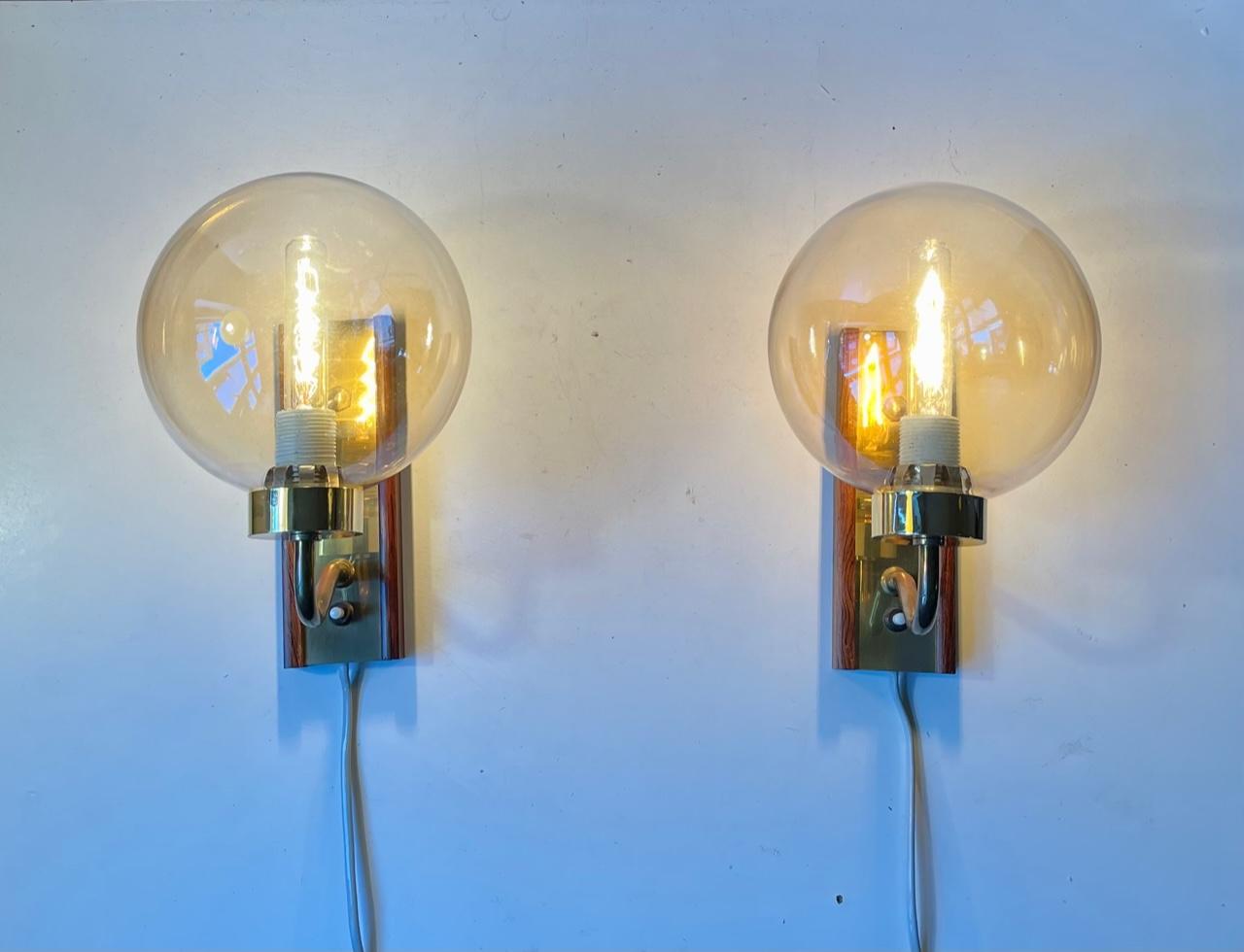 A pair of spherical globe wall lights called soap bubble. Designed and manufactured by Svend Mejlstrøm for his own company in Denmark during the 1960s. They are made from brass, rosewood and hand-blown smoke glass. (slight yellow in tone) They