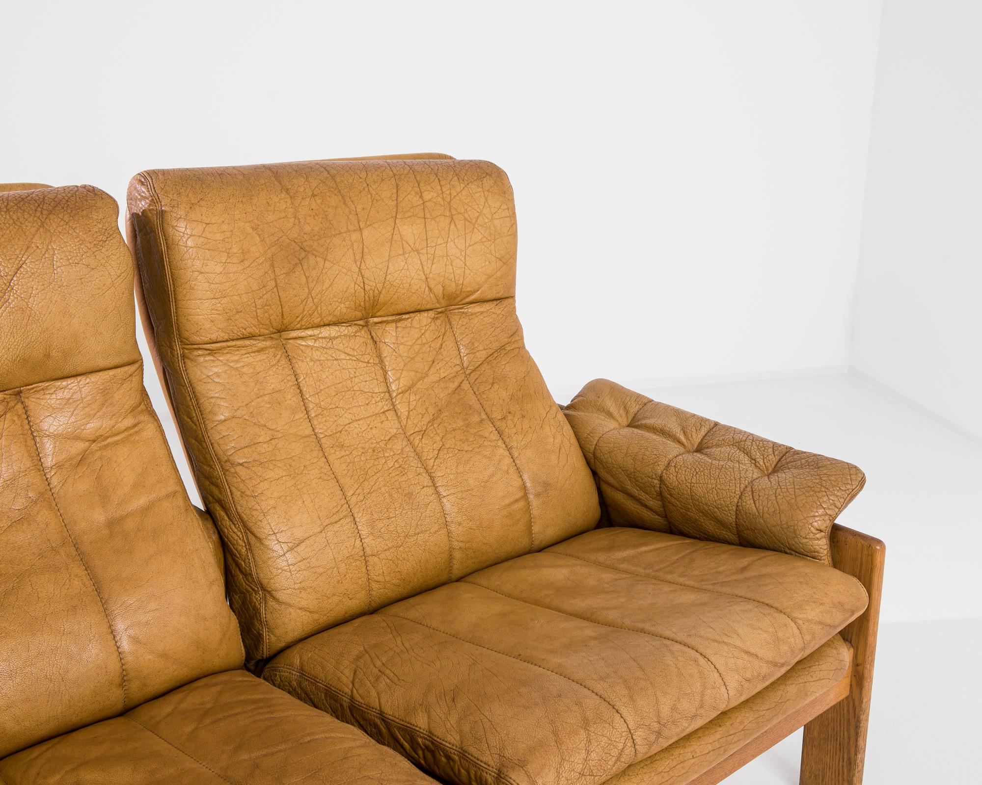 A leather sofa by Skippers Mobler, produced in Denmark circa 1960. A stately, Mid-Century, three-seat sofa in soft sand coloured leather sitting on a sparse wooden frame. Sectioned like a tandem lounger, this classic from the Danish furniture house