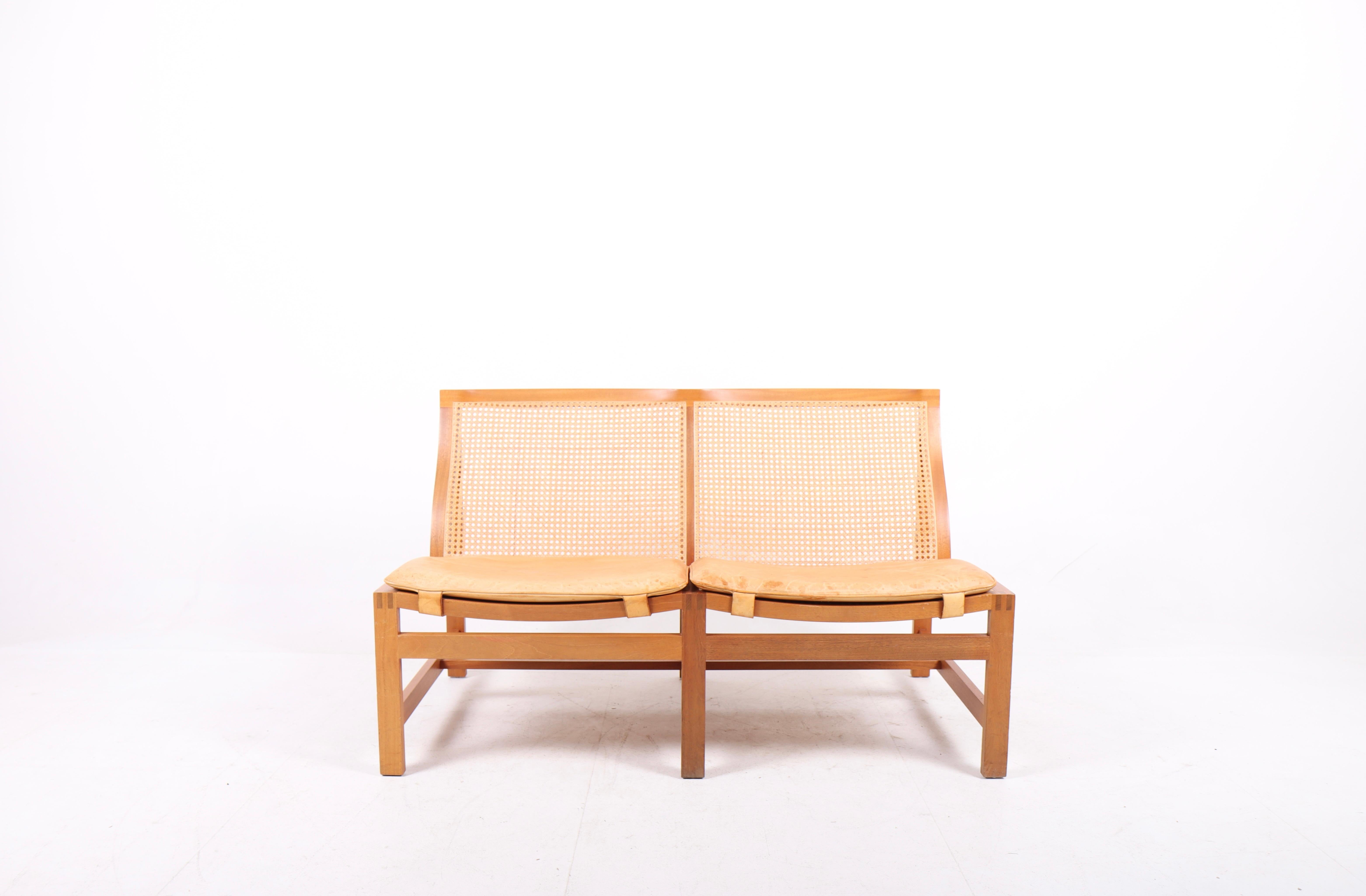 Elegant sofa with mahogany frame and French caning in seat and back. Seat cushion in patinated leather. Designed by Danish architects Johnny Sørensen and Rud Thygesen.