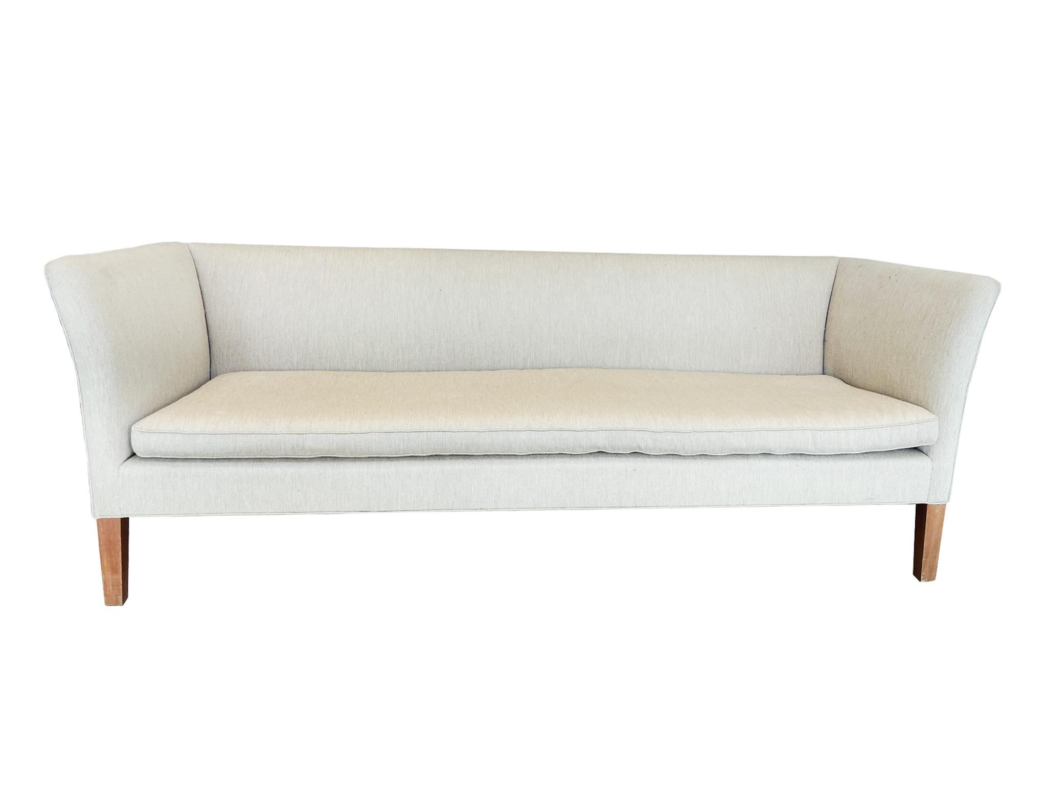 Made in the Mid-20th Century in the style of Frits Henningsen, this Danish Modern sofa has a cream wool upholstery and beech legs. Sleek and subtly rounded lines characterize the sofa's silhouette, giving it a timeless elegance.

Dimensions:
79 in.