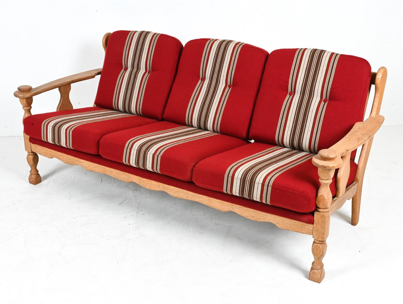 Capture the spirit of the 1970's with this fabulous sofa attributed to Henning Kjærnulf. Crafted from quarter-sawn white oak, the frame features a slatted wingback and sculpted handrests that offer a pleasing tactile experience, a testament to the