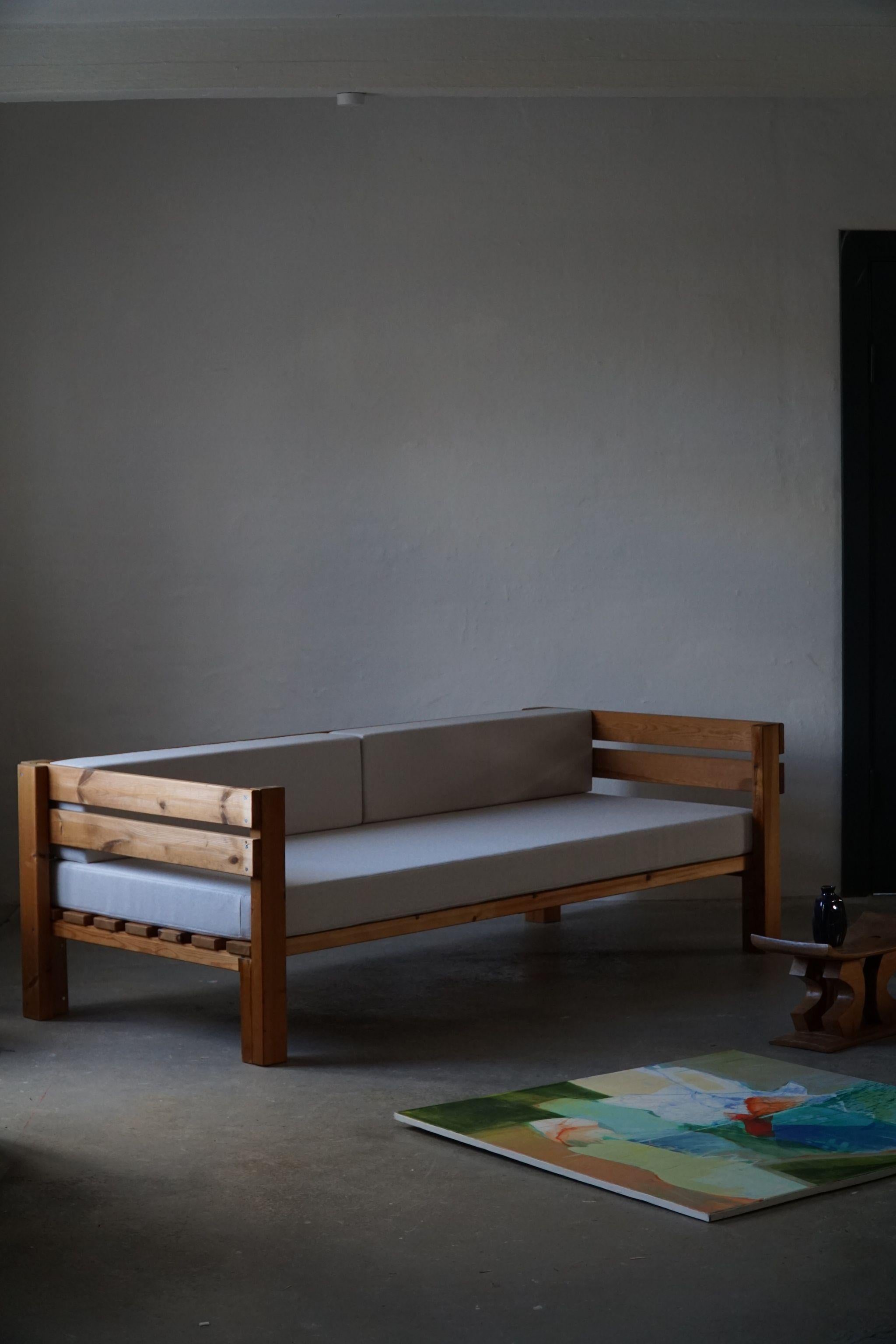 A Danish mid century sofa in solid pine, reupholstered in grey wool. Made by a Danish company 