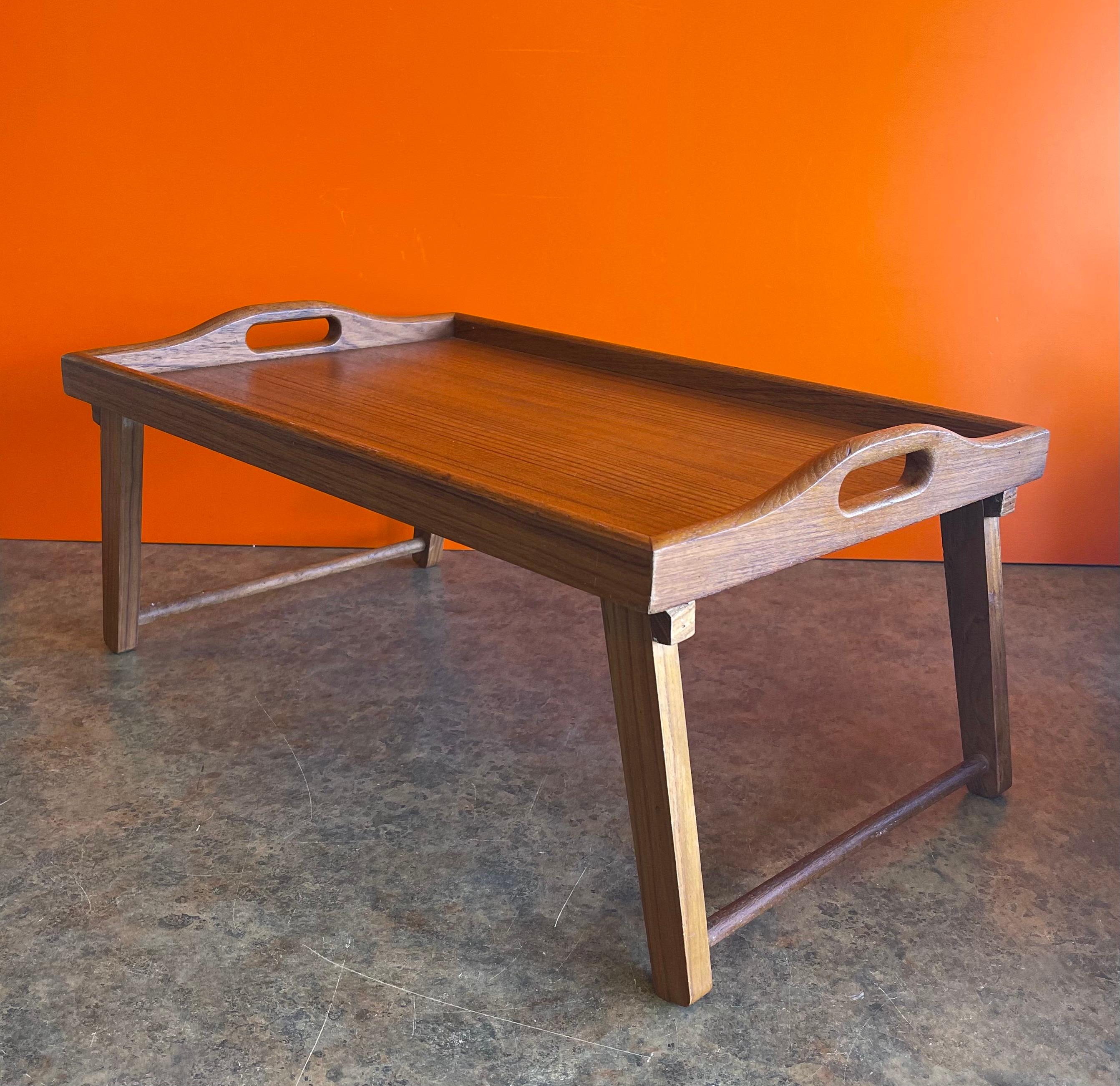 Versatile Danish modern folding teak bed / breakfast tray, circa 1970s. The tray can be used for breakfast in bed with the two foldable legs or as a regular serving tray with the legs in the up position. The piece is in very good vintage condition