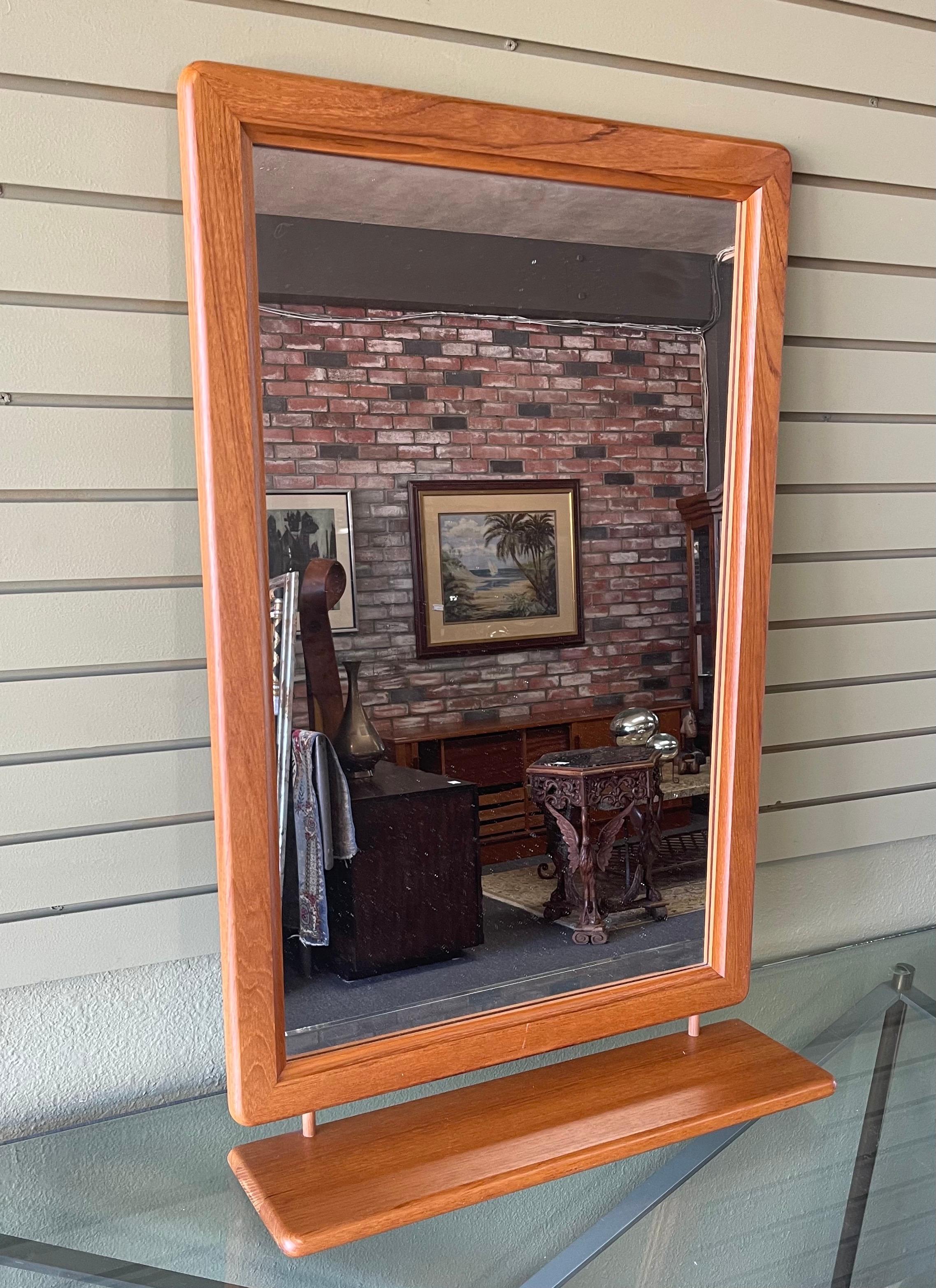 Elegant Danish modern solid teak mirror with rounded corners and shelf, circa 1970s. The large mirror is in great condition with a 2