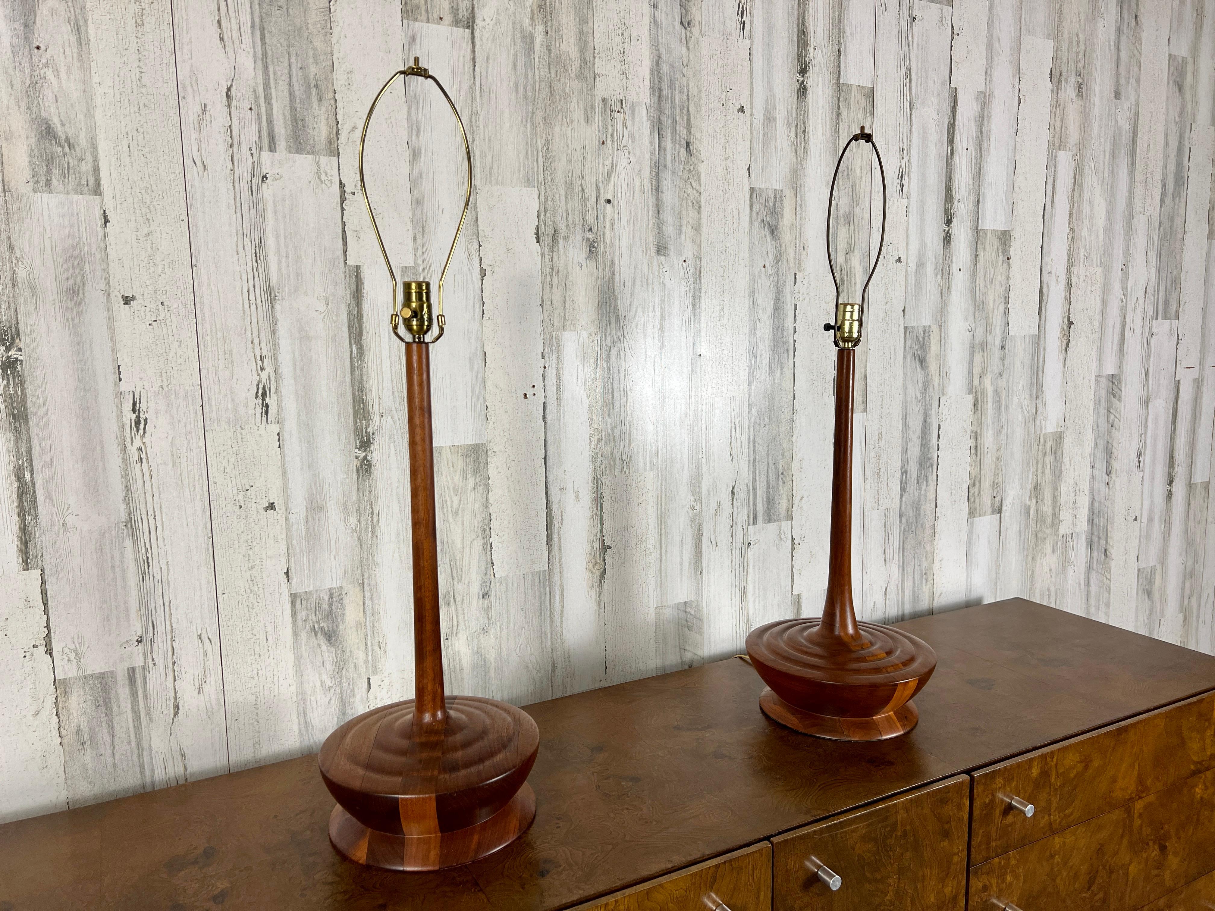 Very tall slender teak pole that protrudes from the ample base with ripple design.
Unusual design make these stunning lamps very pleasing to the eye.
Shades not included.