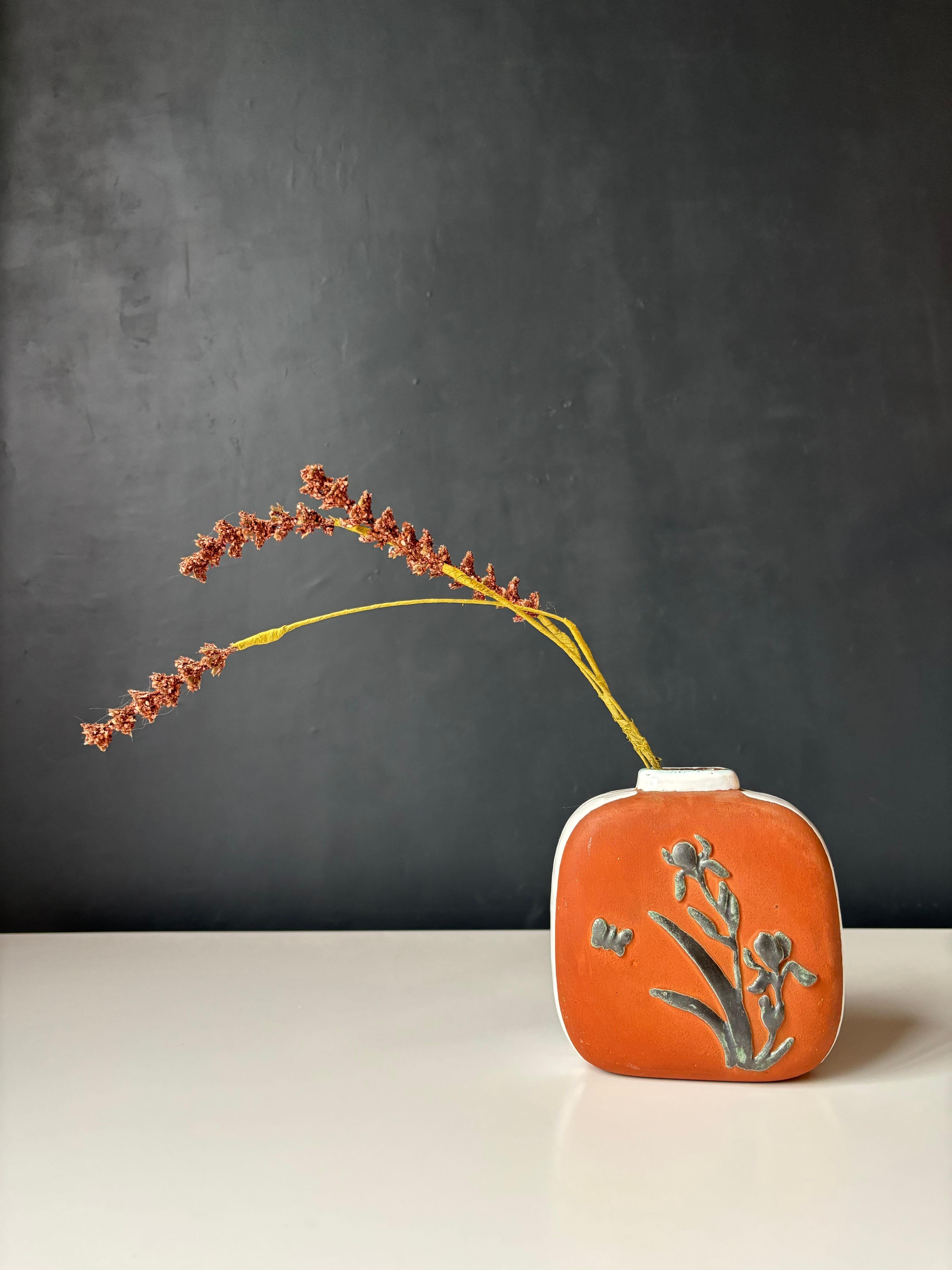 Danish midcentury ceramic vase with floral relief ornaments on front and back on the unglazed brick red body. Shiny white broad lined glaze on sides and top. A Scandinavian piece with a beautiful mix of rustic and delicate decor. Made by Sorgenfri