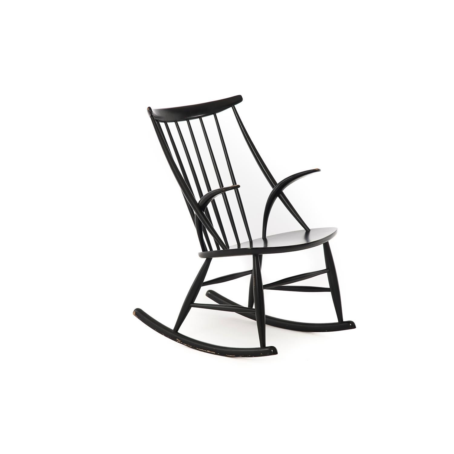 This black lacquered beech Danish modern spindle backed rocking chair boasts truncated arms and a beautiful patina as highlighted in the included photos.