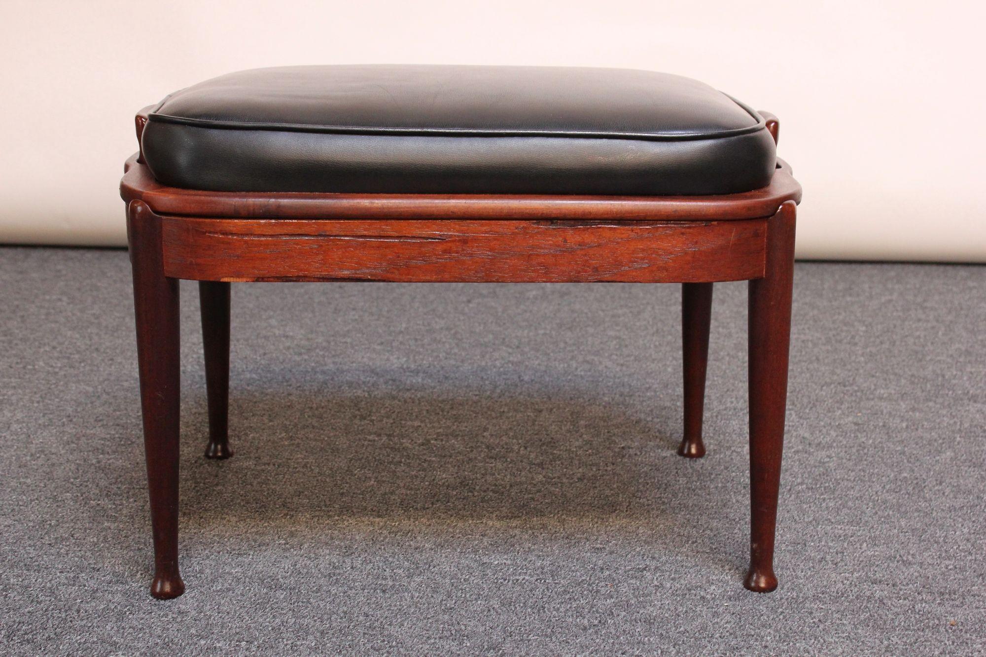 Mid-Century Danish Modern ottoman in stained teak with black vinyl upholstered seat / cushion (ca. 1960s). Cushion is in good, vintage shape, and teak has been newly refinished; only light wear remains, as shown.
Measures: H: 15.5