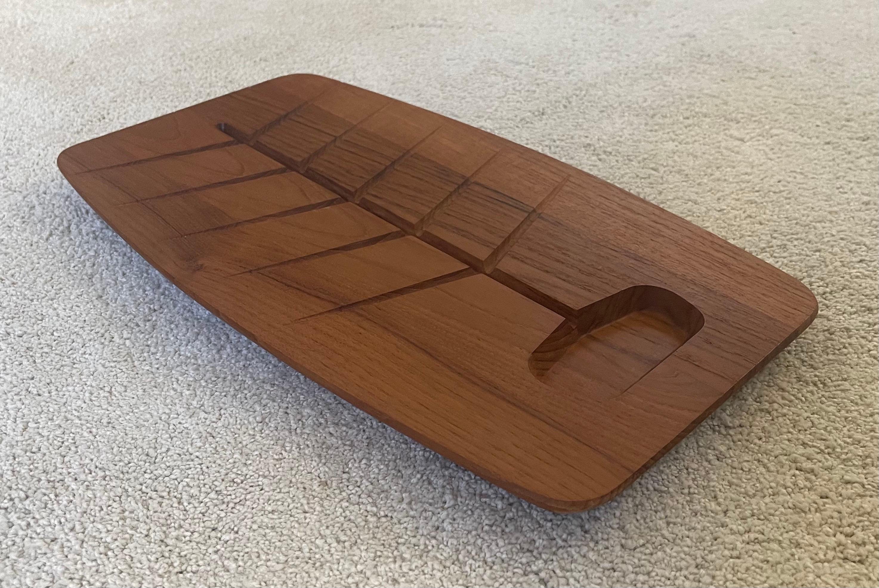 Danish modern staved teak surfboard style carving / cutting board in the style of Dansk, circa 1960s. The piece is very well made with a nice beveled edge and a built in drain for juices. 