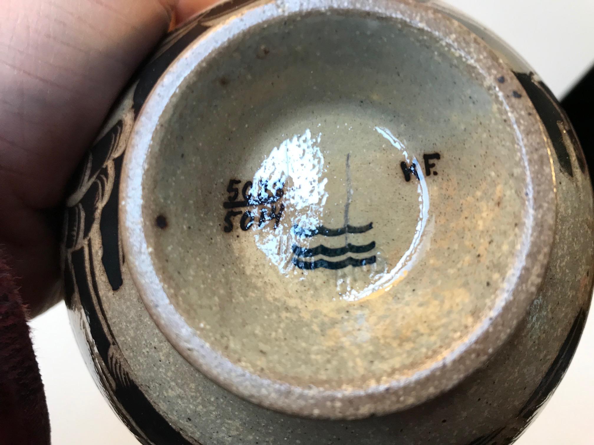 Footed stoneware bowl with black flowers, cliffs and a small black man. Designed by Gerd Hjort Petersen during the 1960s and manufactured by Royal Copenhagen. Fully marked, numbered and signed to the base.