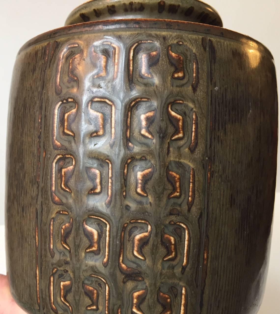 This stoneware vase was designed by the Danish ceramist Valdemar Petersen and manufactured by Bing & Grøndahl or B&G in Copenhagen, Denmark during the 1960s. This is the larger version in this line and it retains the design number: 7228. It is