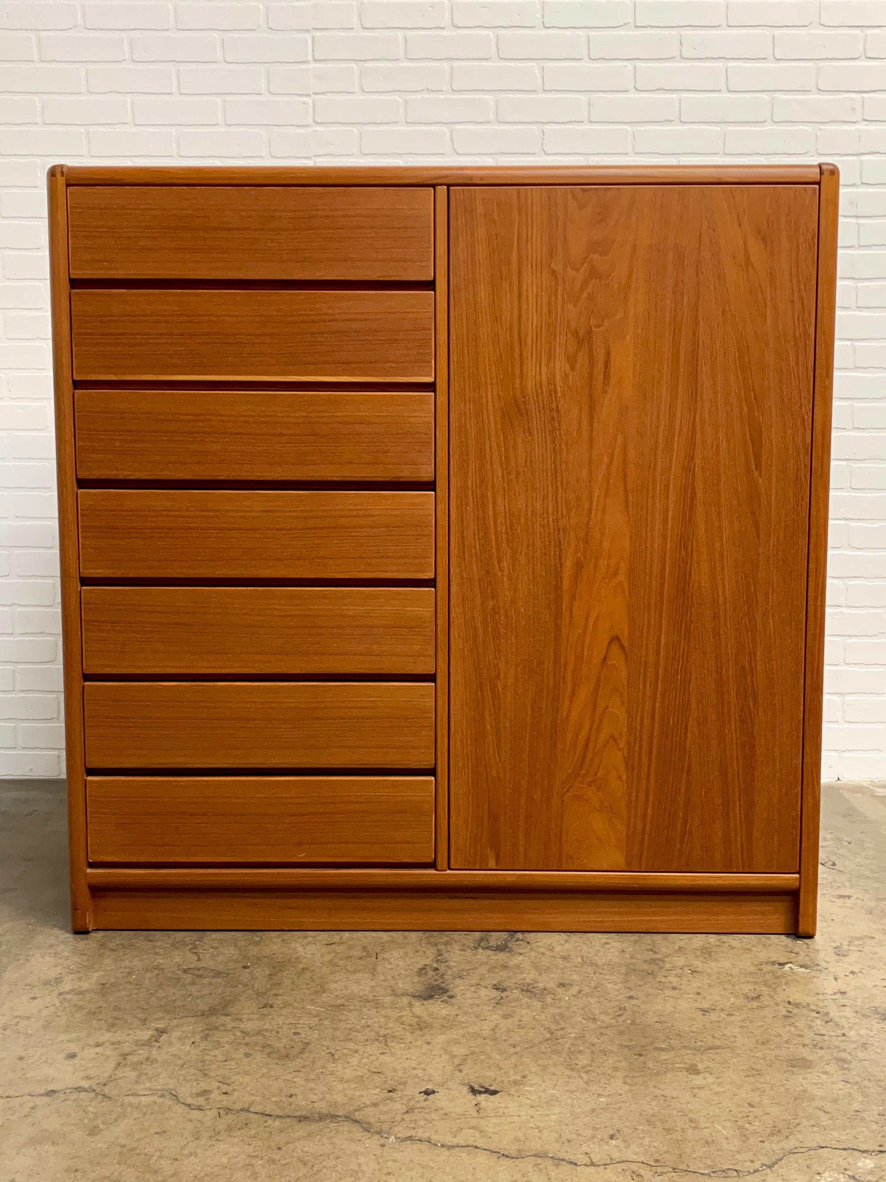 Teak armoire with seven drawers and a right hand door that has two adjustable shelves and one small accessory drawer in the Danish modern highboy style.