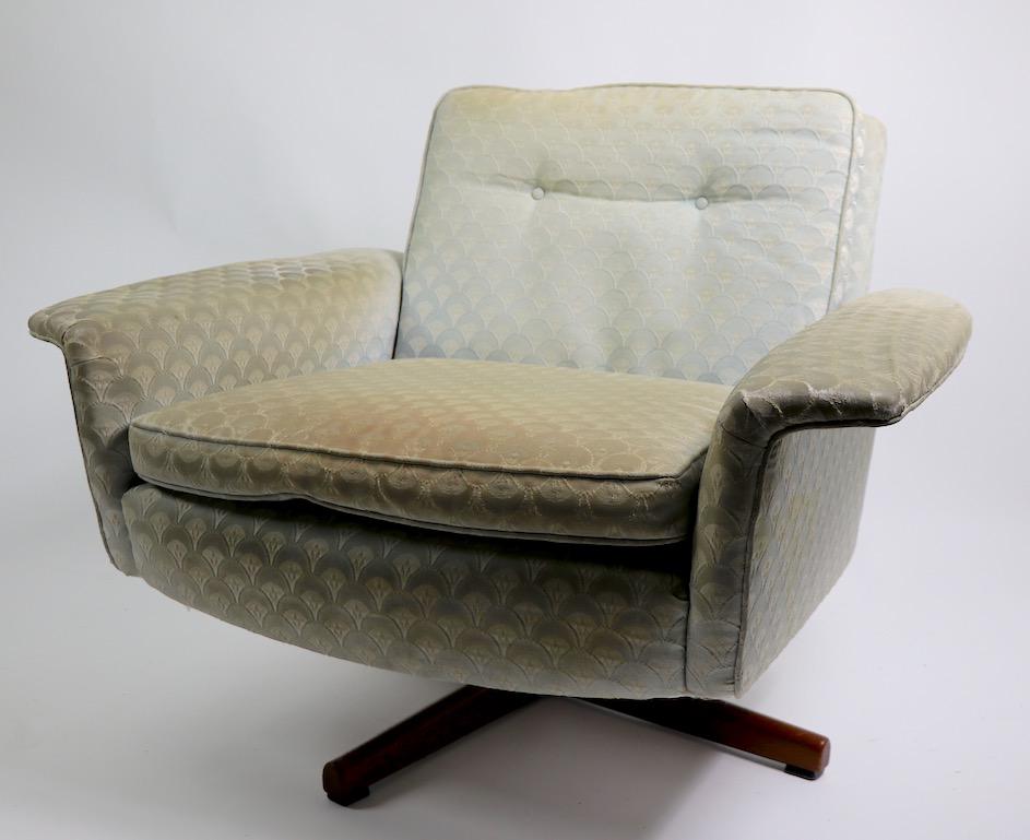 Very stylish Danish modern swivel chair and matching ottoman, with upholstered seat and back on teak star bases. Top quality design, materials, and construction, attributed to DUX, but unsigned. The upholstery is worn and will need to be replaced.