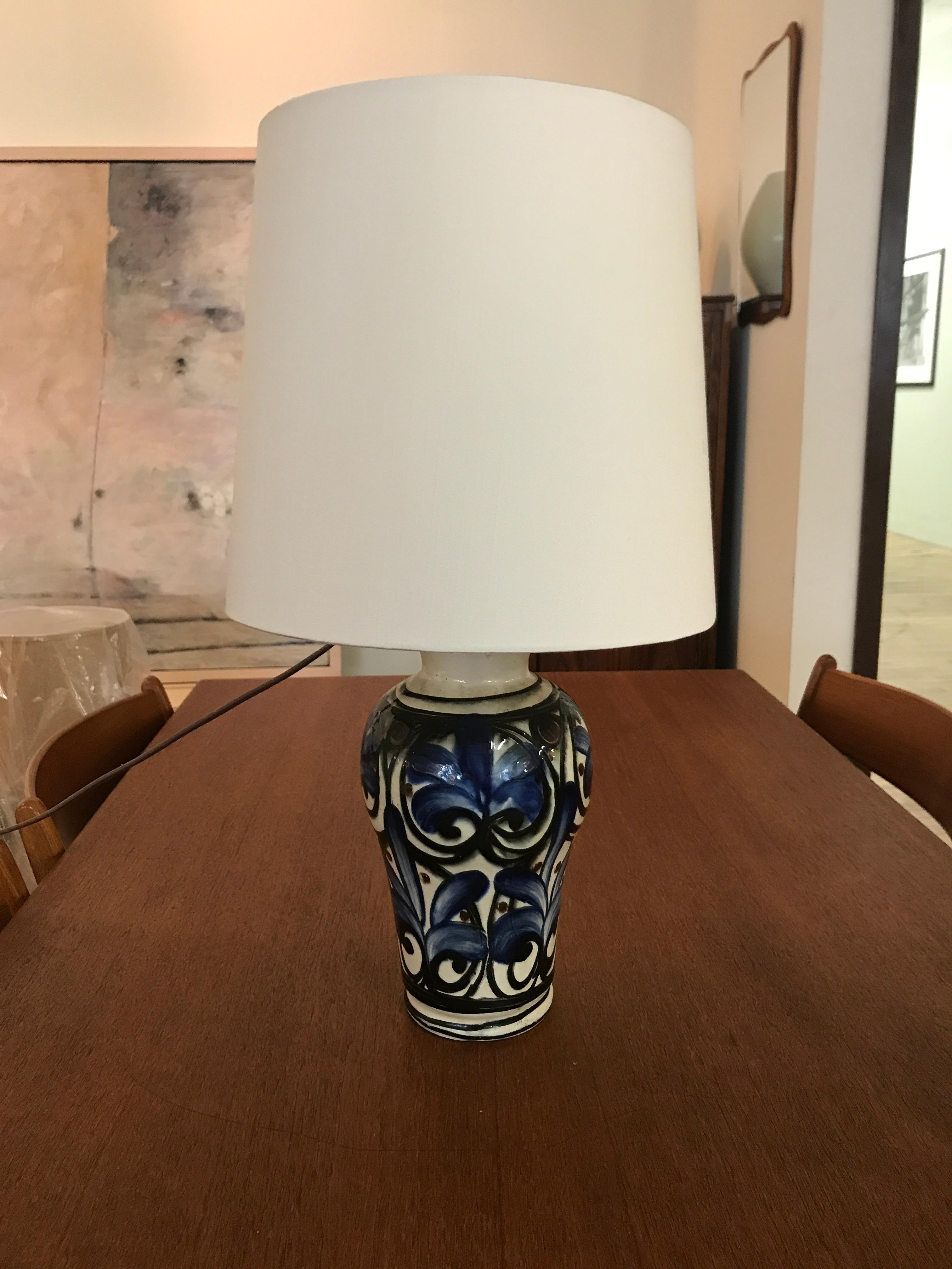 This large Danish modern table lamp boasts a blue, cream, brown and black floral motif, created by hand and therefore one of a kind. New linen shade. Diameter 4