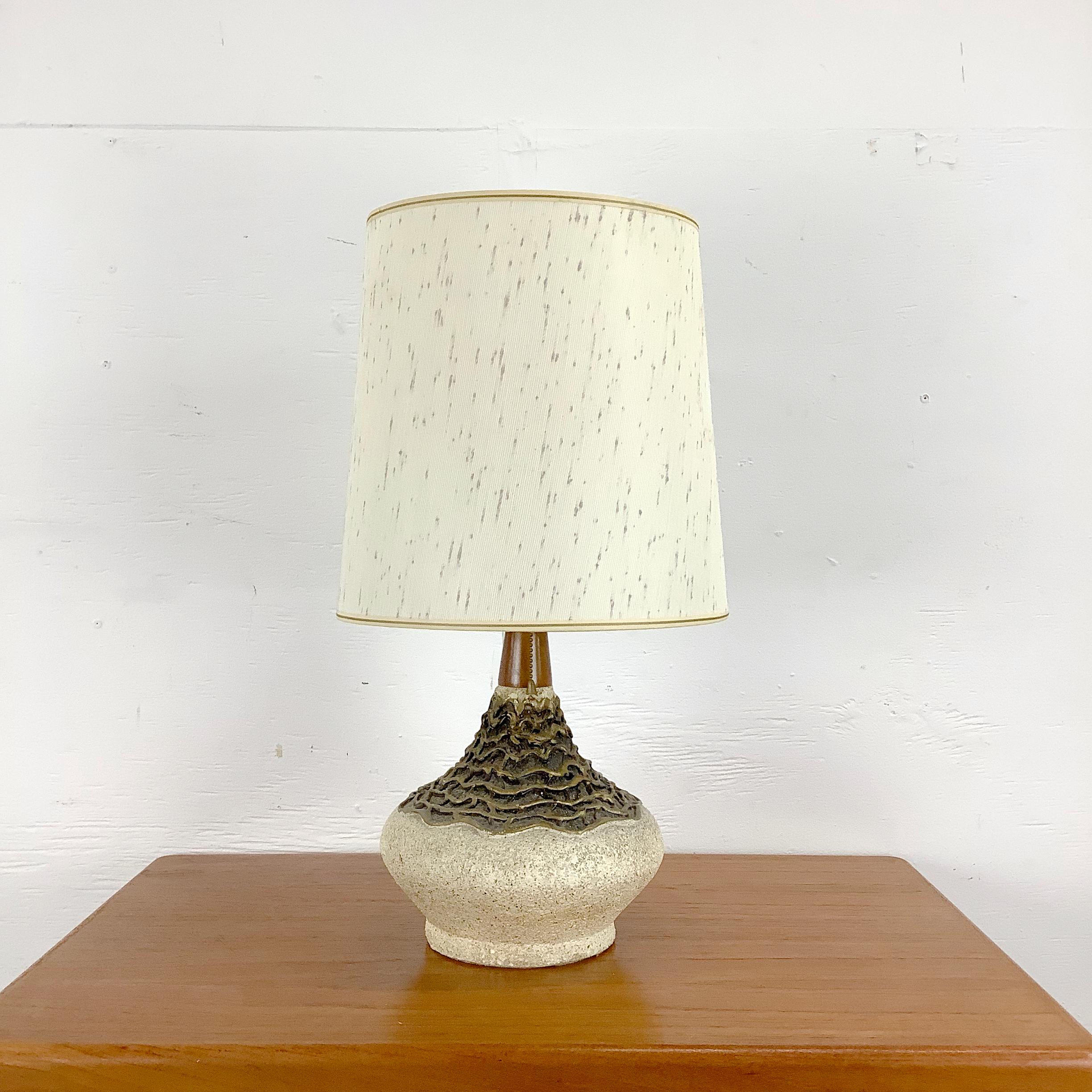 Témoignage de l'artisanat du milieu du siècle, cette lampe en poterie danoise associe un design organique à un raffinement discret. La base présente une forme en céramique sculptée avec une texture complexe en couches, évoquant des éléments naturels