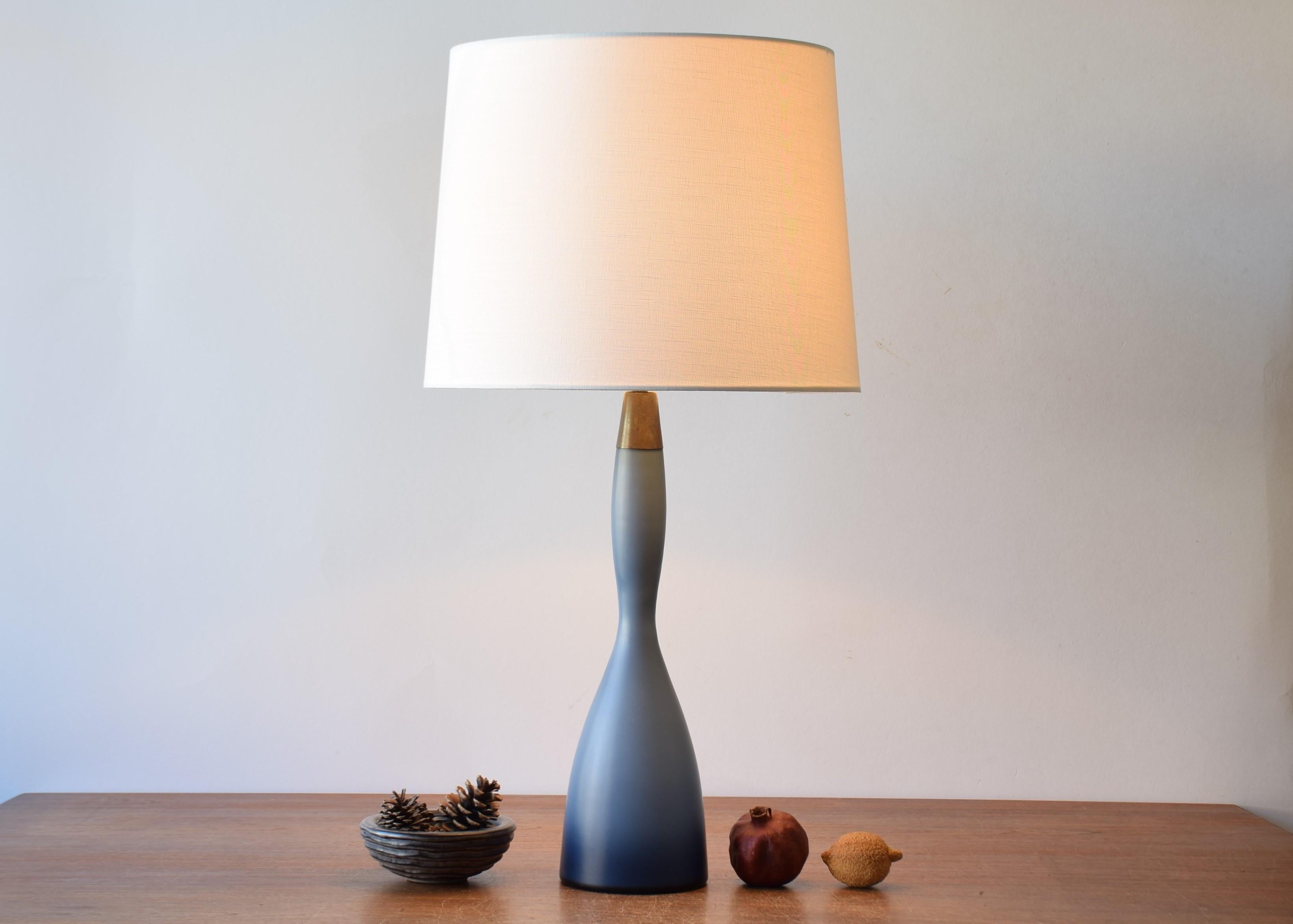 Lampe de table haute, fine et élégante du fabricant danois Kastrup Glasværk (plus tard Holmegaard Glass).
Elle est fabriquée dans un verre dépoli bleu poussière de rêve appelé 