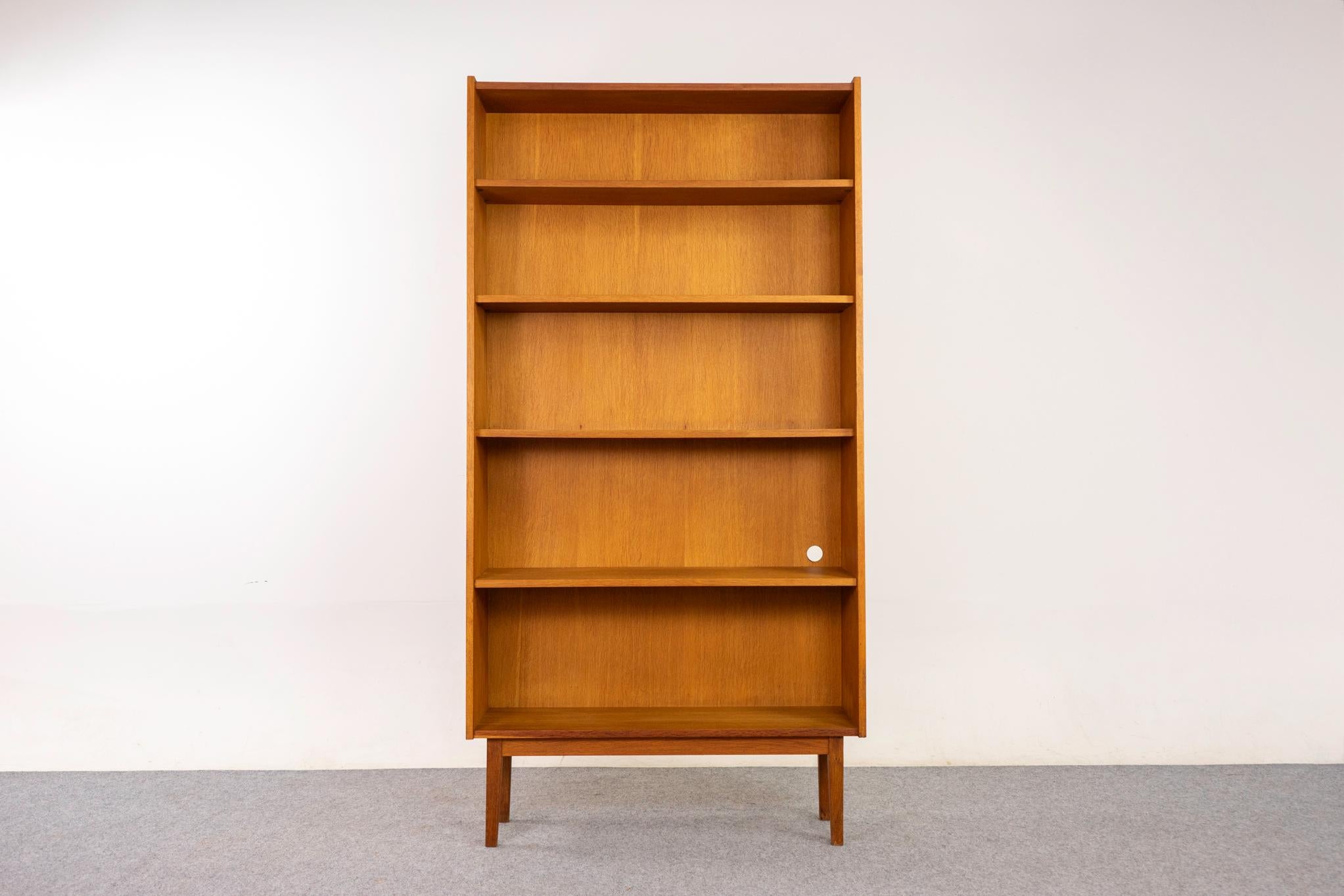 Dänisches Bücherregal aus Eiche, circa 1960er Jahre. Verjüngtes Profil mit farblich abgestimmtem Furnier und massivem Sockel. Mittlere Ablage in fester Höhe, 3 verstellbare Einlegeböden.

Unrestauriertes Exemplar mit der Option, es für zusätzliche