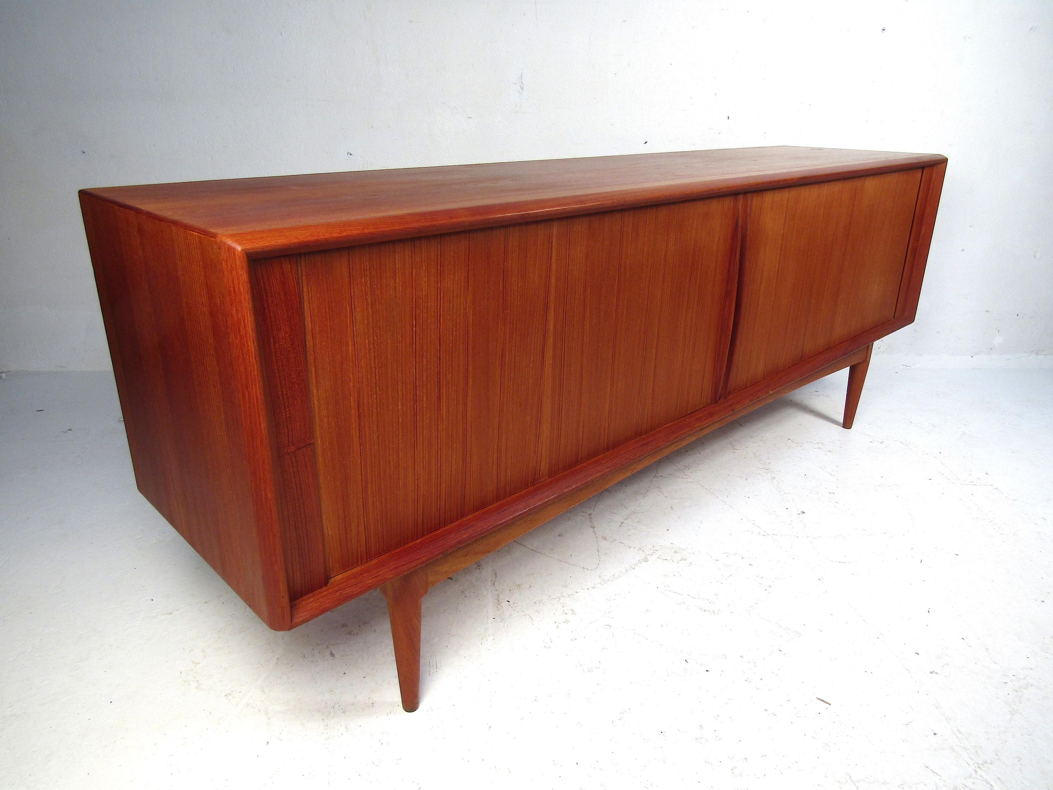 Stunning midcentury Danish credenza manufactured by Bernhard Pederson and Son. Long case piece with well-made tambour doors concealing the interior. Within the credenza are two sections of adjustable shelving, along with two dovetail-jointed drawers