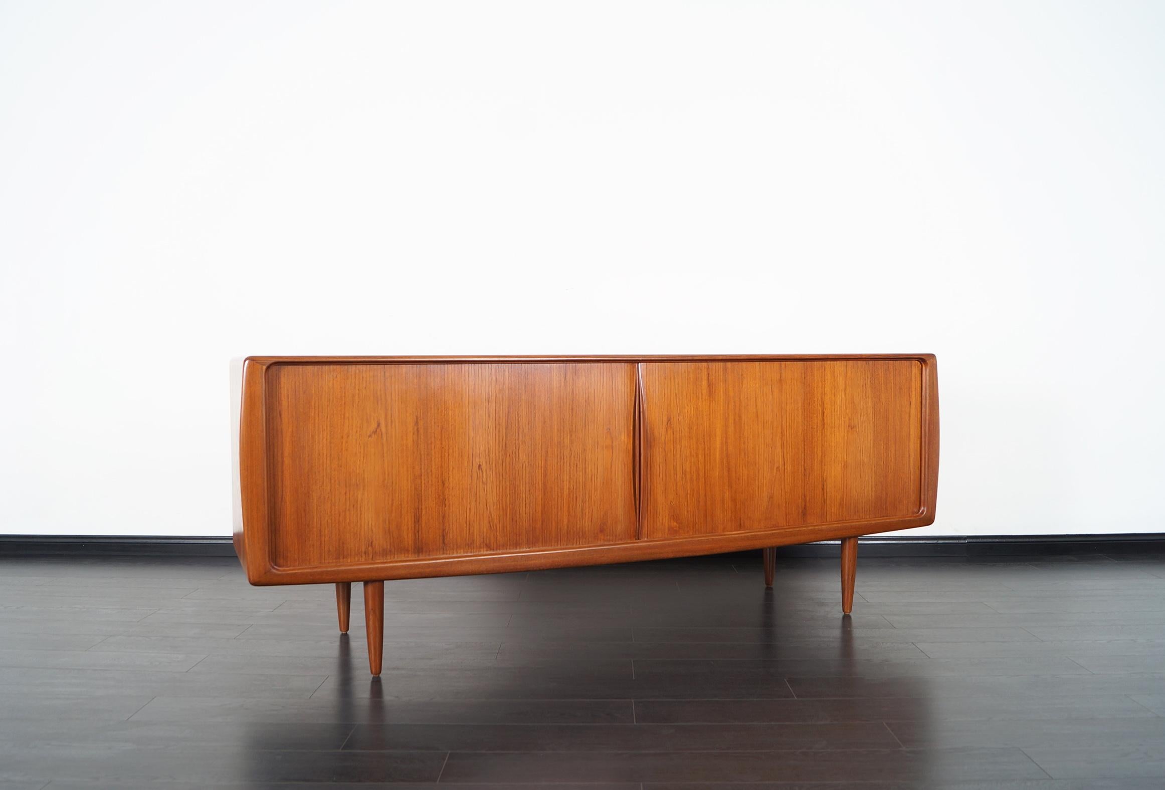 Exceptional Danish modern tambour door credenza designed by Hoss Wulff. Features two sliding tambour doors that opens up to three sections. The middle section has eight pull out trays. The sections on each end has a total of three adjustable