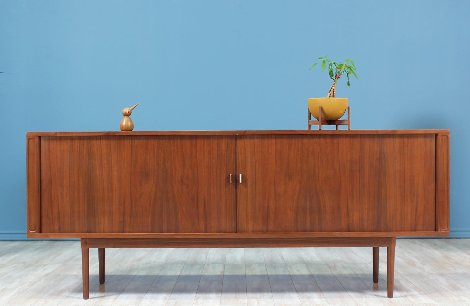 Elegant credenza designed and manufactured by Peter Løvig Nielsen in Denmark, circa 1970s. Featuring a walnut wood construction with seamless tambour doors adorned with subtle aluminum-accented pulls. The doors open smoothly to reveal ample storage