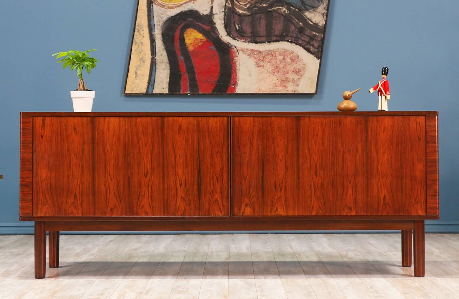 Rosewood Tambour Door Credenza designed and manufactured by Hornslet Møbelfabrik in Denmark circa 1960’s. This iconic Danish Modern piece features a striking Brazilian rosewood grain throughout. The tambour doors open effortlessly to reveal an oak