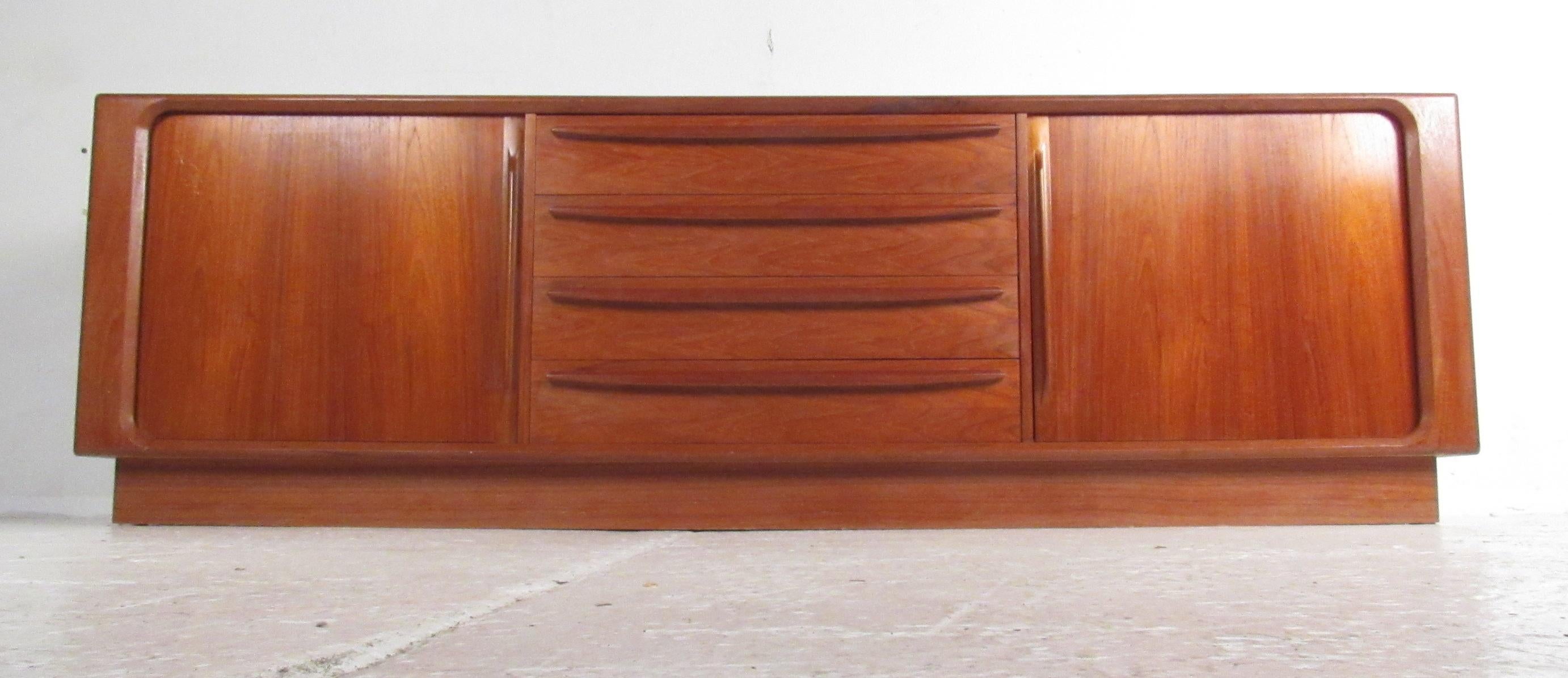 Beautiful tambour door teak sideboard manufactured in Denmark in the 1960s. Four large center drawers are flanked by a pair of tambour doors revealing an adjustable shelf on one side and three tray drawers on the other. The finished backside allows