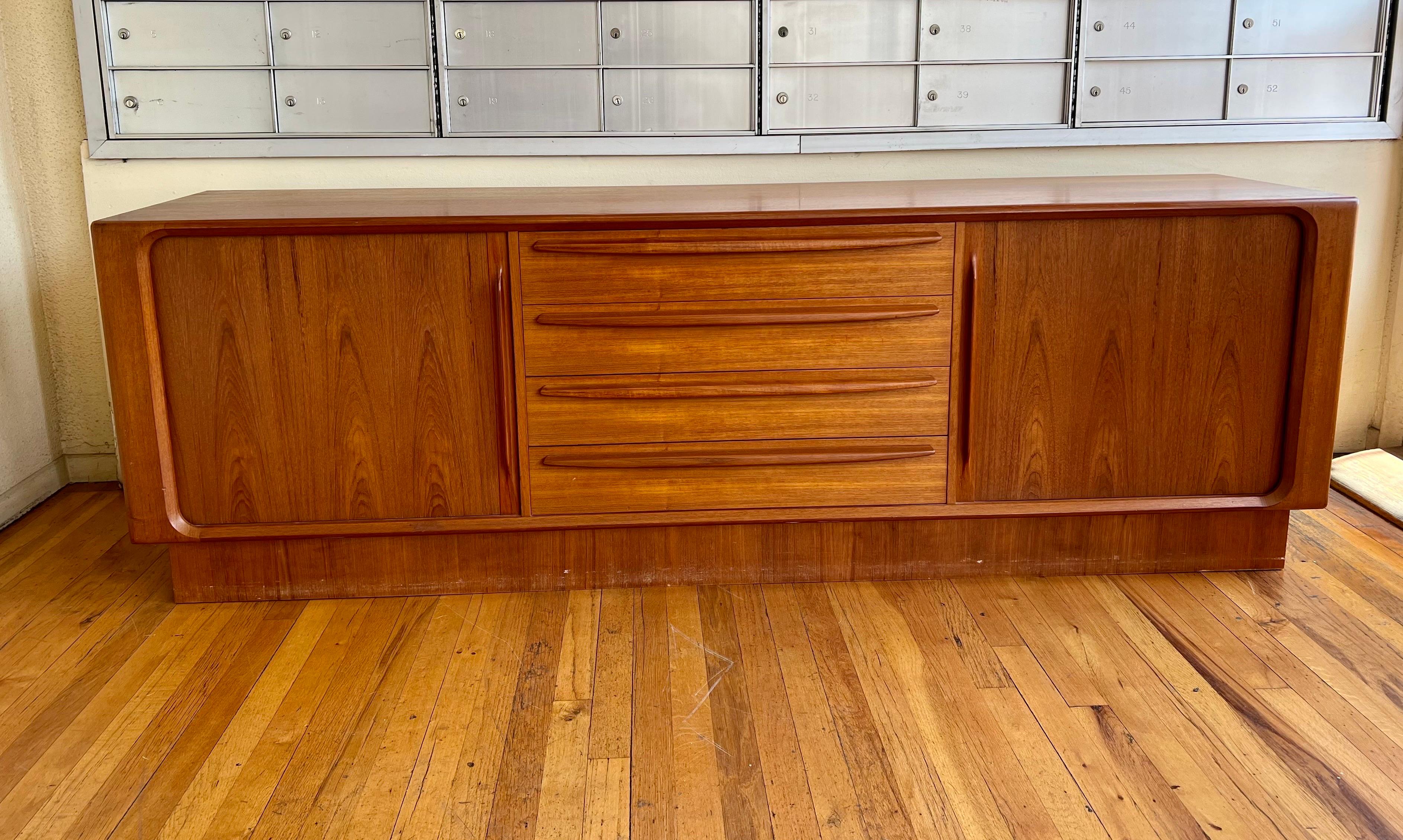 Beautiful Danish modern low tambour door teak credenza sideboard manufactured in Denmark in the 1960s. Four large center drawers are flanked by a pair of tambour doors revealing an adjustable shelf on one side and three tray drawers on the other.