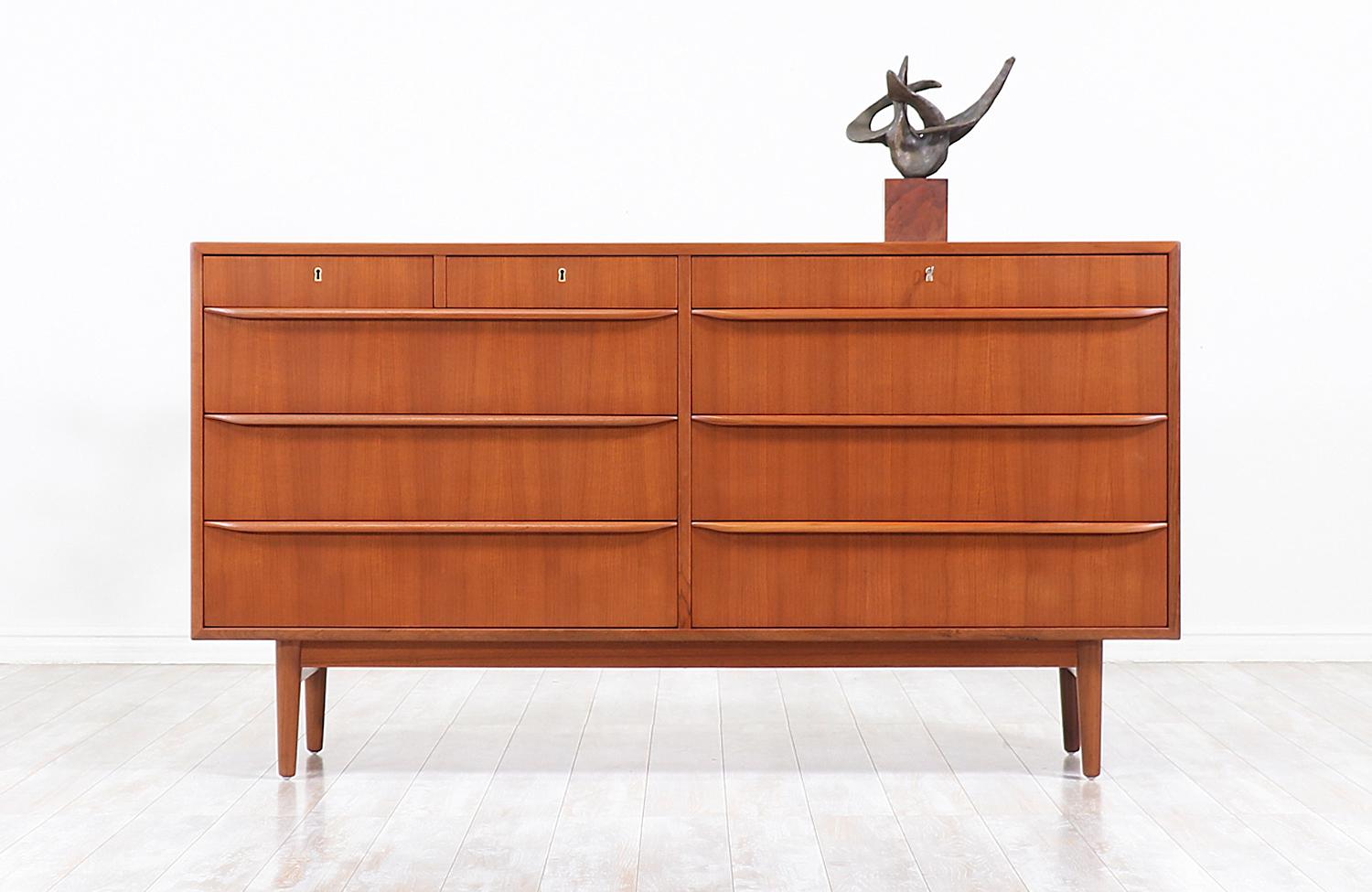 Stylish Danish modern dresser designed and manufactured in Denmark, circa 1960s. This versatile and compact nine-drawer dresser features a solid teak wood case with nine book-matched drawers and carved recessed pulls that complete a clean aesthetic