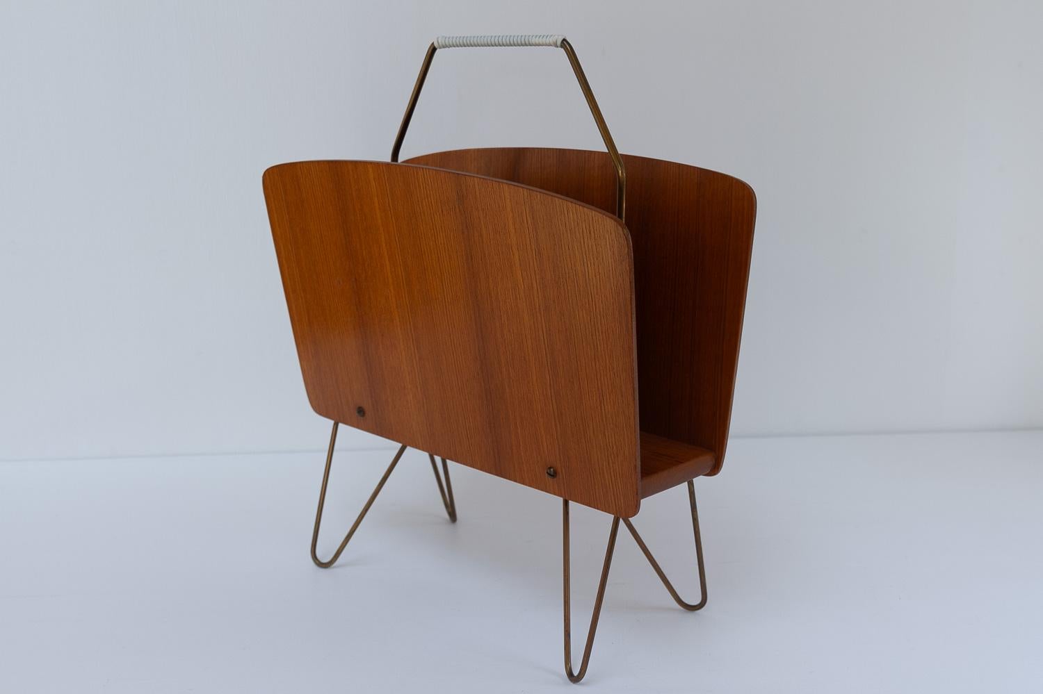 Danish Modern Teak and Brass Magazine Rack, 1950s.

Vintage Danish Mid-Century Modern magazine stand/newspaper holder in teak with hairpin legs and handles in brass. The brass handles are wrapped with a white cord.

Elegant and light, the perfect