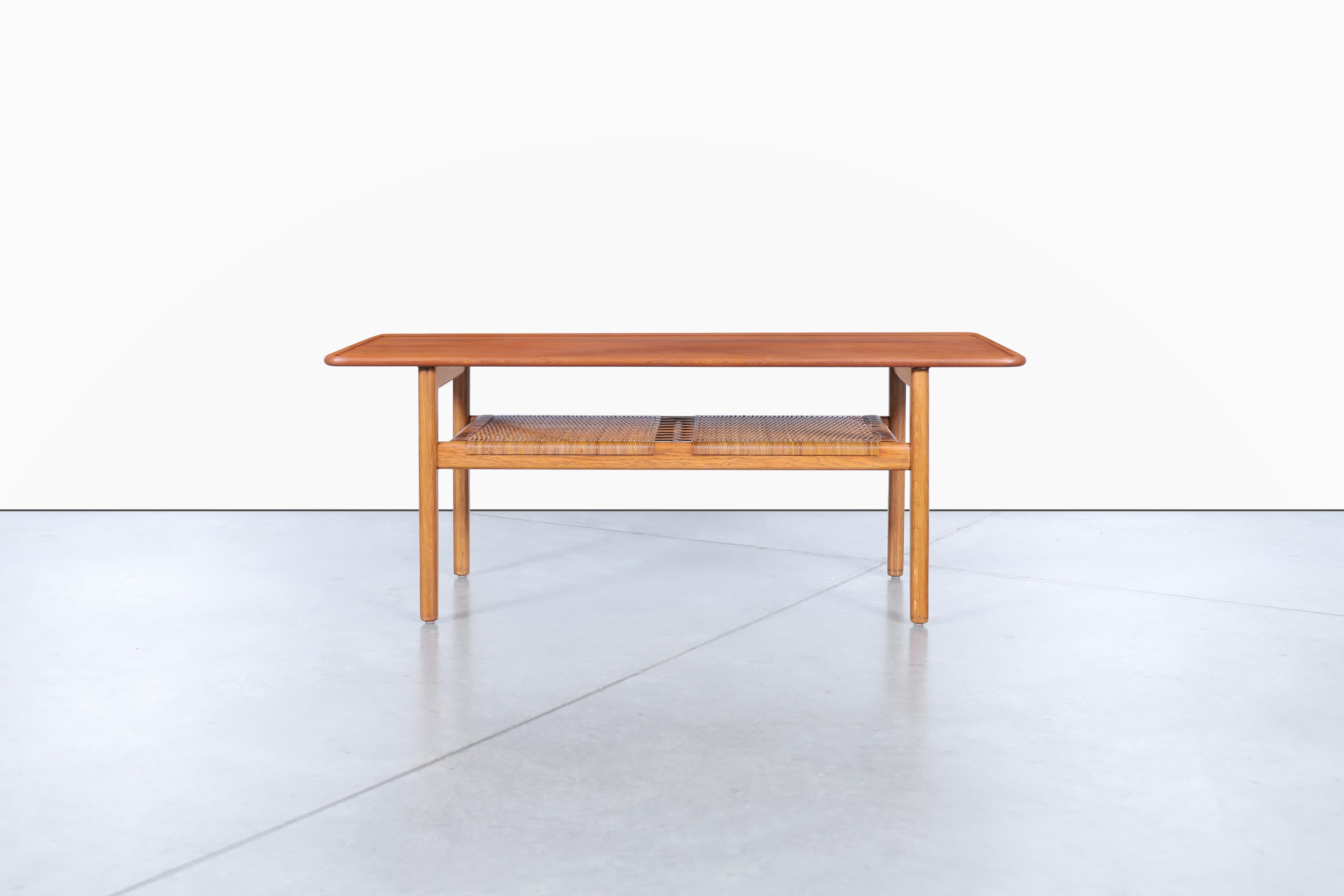 Cette élégante table basse moderne danoise en teck est un véritable bijou des années 1950, conçu par le célèbre Hans J. Wegner pour Andreas Tuck. La table modèle AT-10 présente un plateau en teck massif avec un rebord en relief magnifiquement