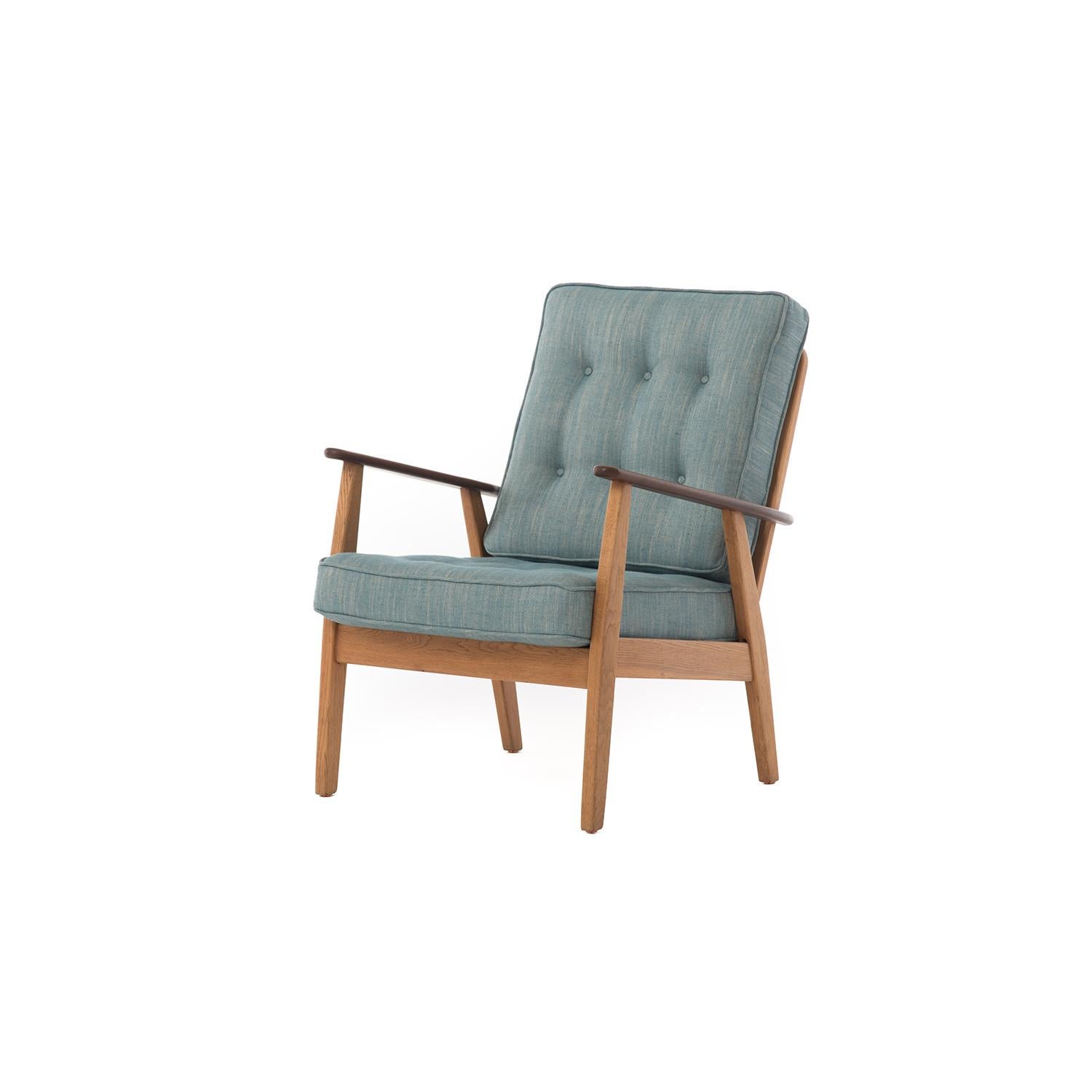 This 1950s midcentury lounge chair boasts a solid oiled oak frame and sculptural teak arms, material choices that are of the era. The newly upholstered cushions in cadet blue linen provide a comfortable spot for relaxing after a day of adventure.
