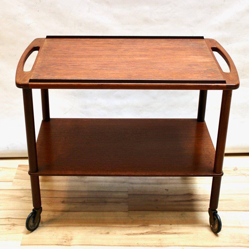 Mid-century Danish Modern teak bar cart with sculpted cutout pulls. The cart has two levels and sits on casters. In excellent condition. 

Measures: width: 29 in / depth: 17.5 in / height: 23.5 in