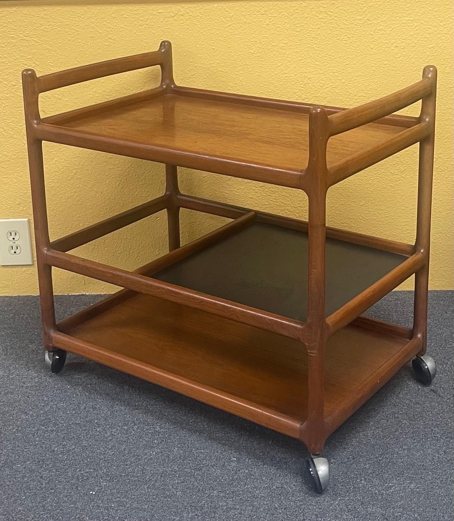 Gorgeous Danish modern teak bar cart / serving trolley with shelves by Johannes Andersen for Silkeborg, circa 1960s. Elegant and simply designed Danish bar cart on gliding wheels. Beautifully detailed wooden joints and structure that encourages you
