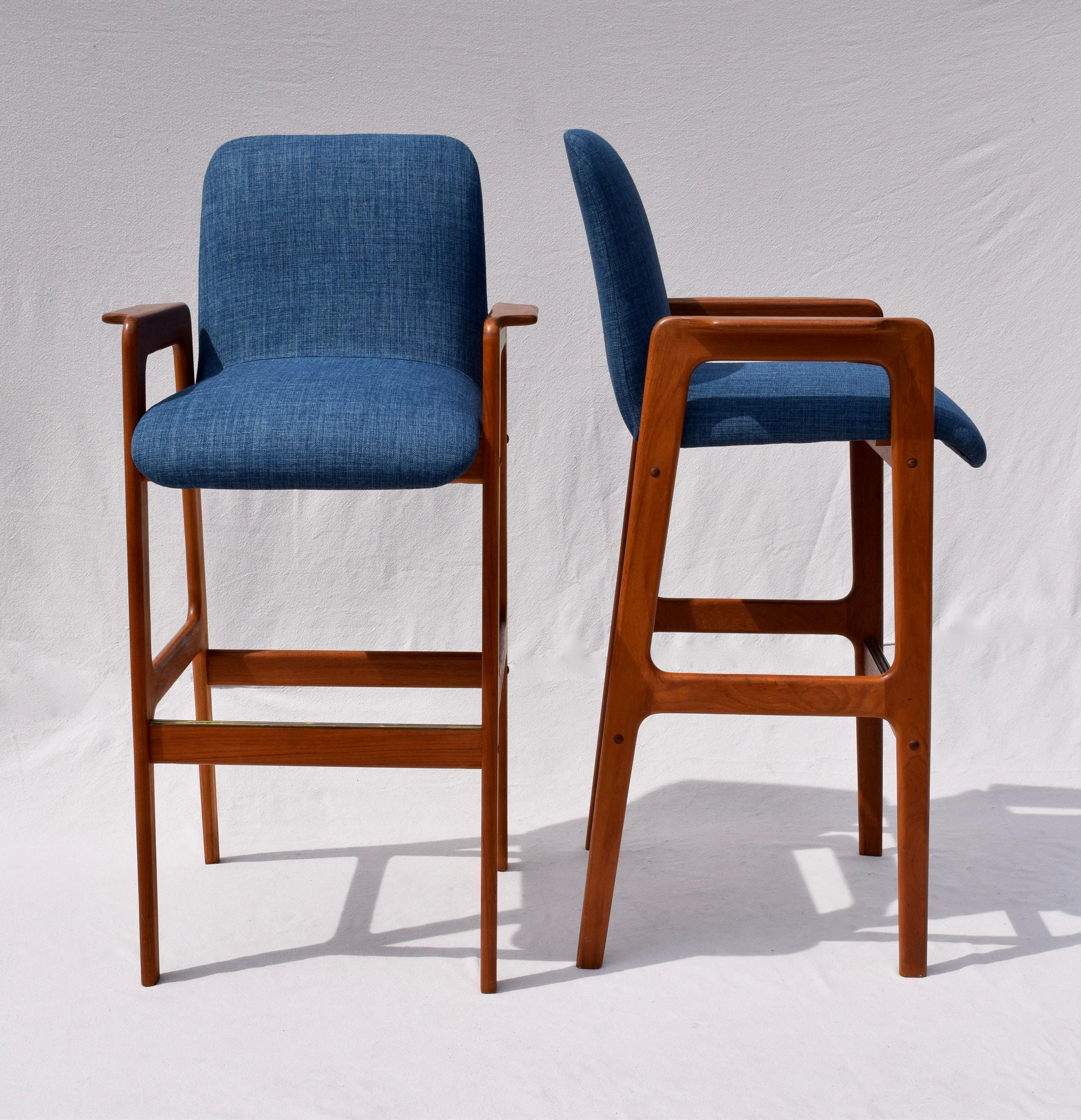 Danish modern pair of teak bar stools with brass lined foot rail and new indigo blue upholstery, circa 1970s.