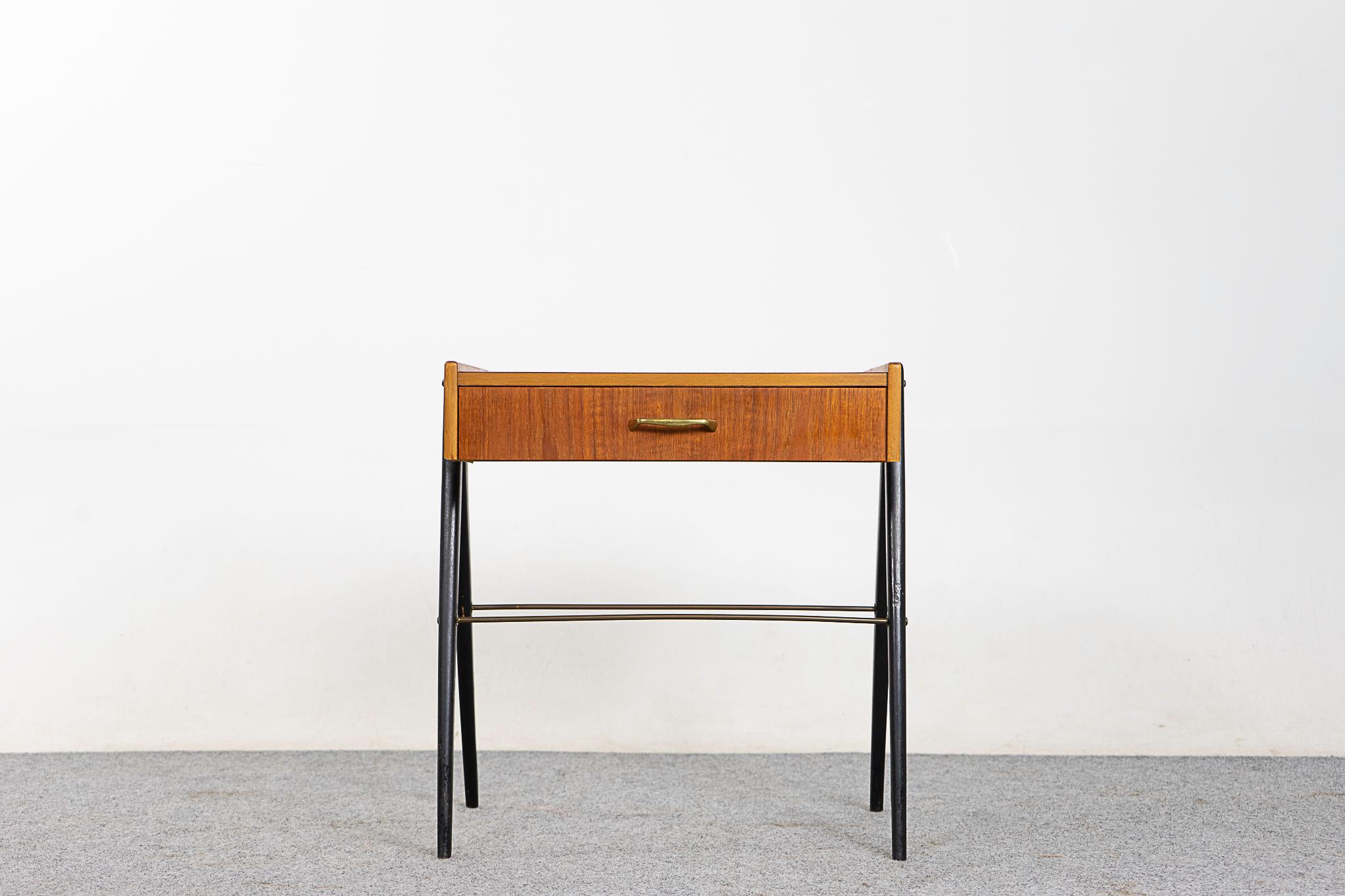 Teak midcentury bedside table, circa 1960s. Dovetailed drawer for your small items, beautifully veneered case rests on slender splayed black legs with contrasting metal supports.

Unrestored item, some very minor marks consistent with age.

Please