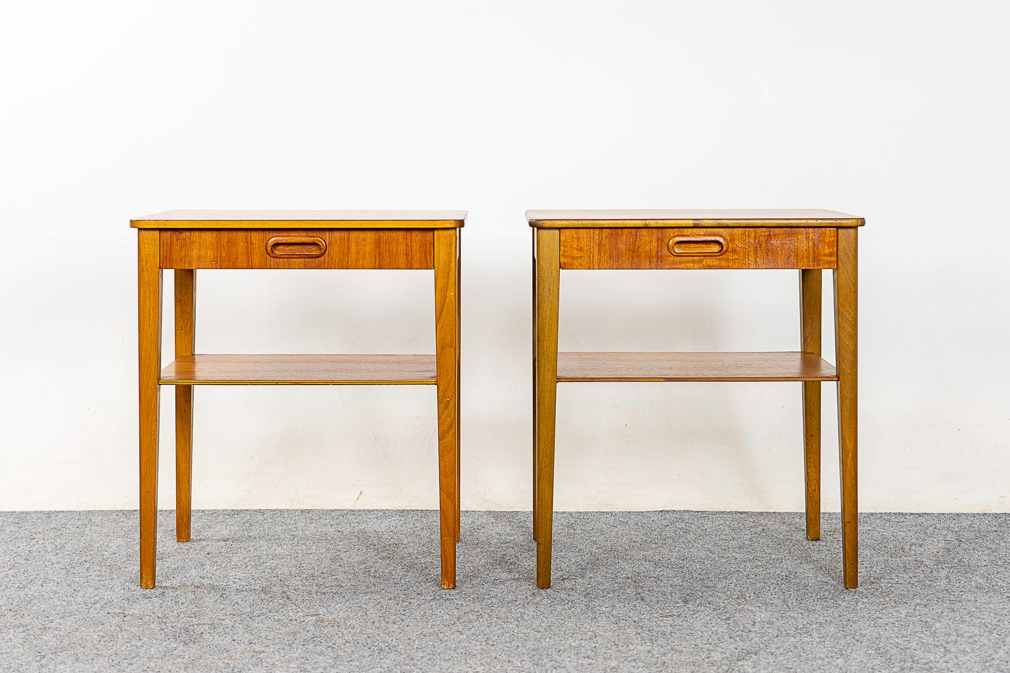 Teak & beechwood bedside table pair, circa 1960s. Beautifully veneered case rests on slender, tapered legs. Dovetailed drawer offers storage for small items, and the lower shelf is perfect for your favorite book. Simple, elegant!

Unrestored item,