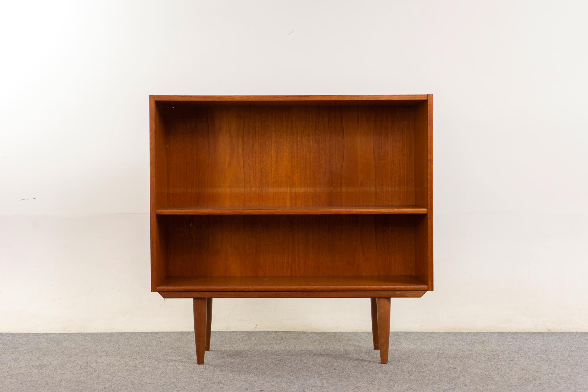 Libreria danese in teak, anni '60 circa. Cassa impiallacciata in teak con ripiano regolabile ed eleganti gambe affusolate.

Articolo non restaurato con la possibilità di acquistarlo in condizioni restaurate con un supplemento di 200 dollari. Il