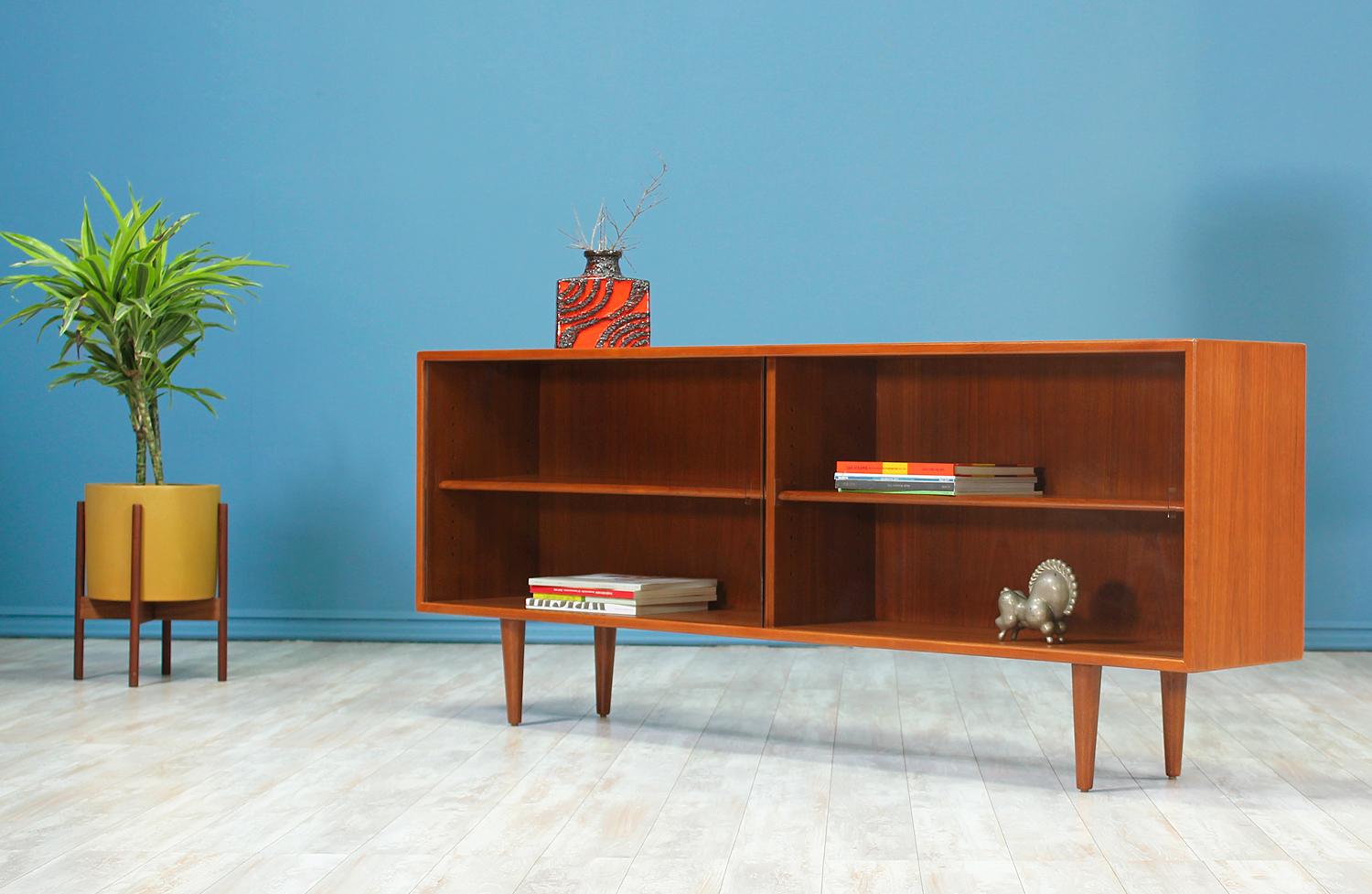 Danish Modern Display Case designed and manufactured in Denmark circa 1960’s. Beautifully crafted in rosewood, this stunning bookcase sits on 8” tapered legs and features two compartments with removable glass shelves. The glass doors permit the