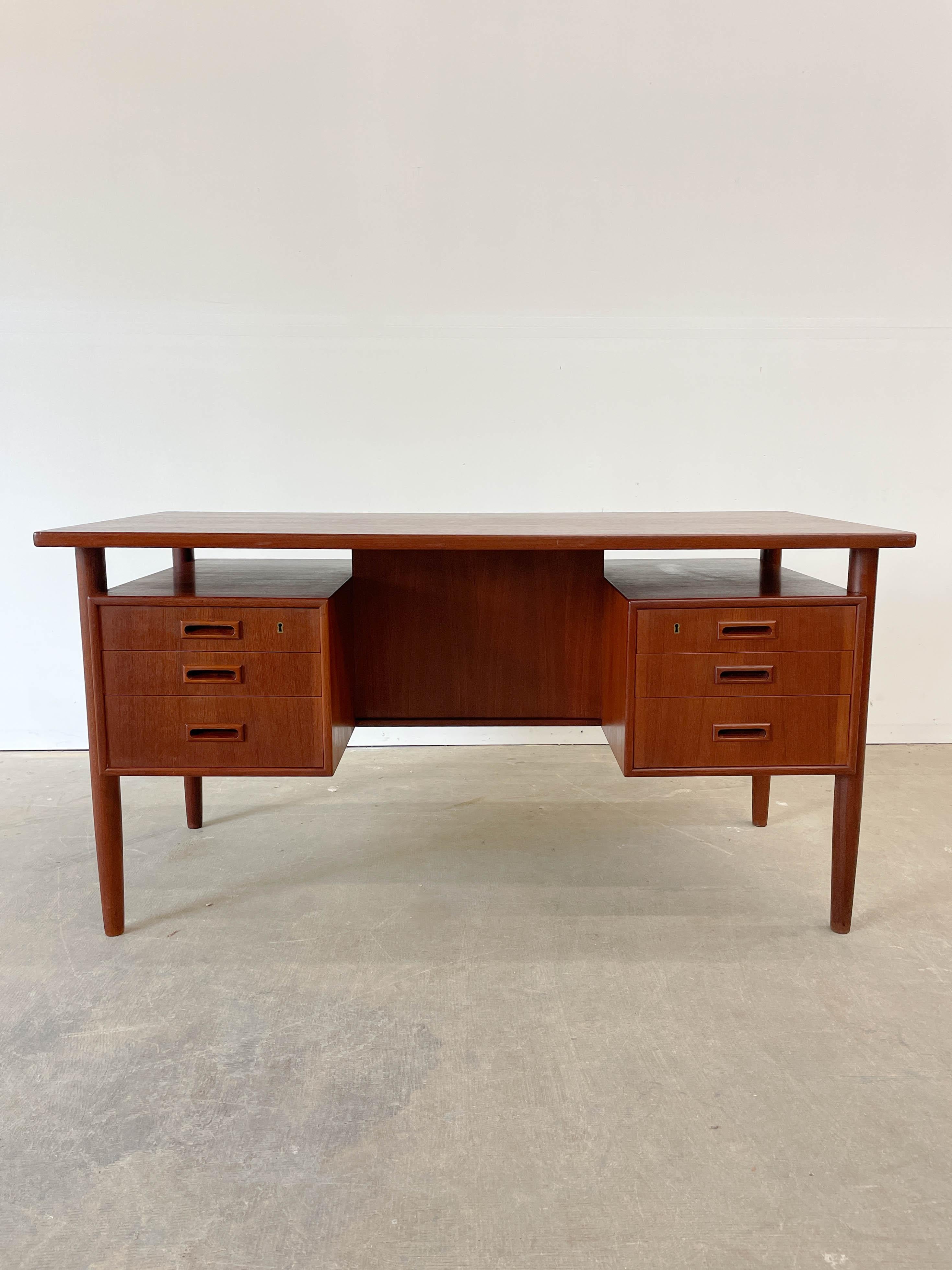 Superbly proportioned Danish teak desk with rear bookshelf and floating pedestals from the 1950s. This design has been attributed to designer Arne Vodder for Sibast by other sellers but we have not found docunmentation for this. Excellent