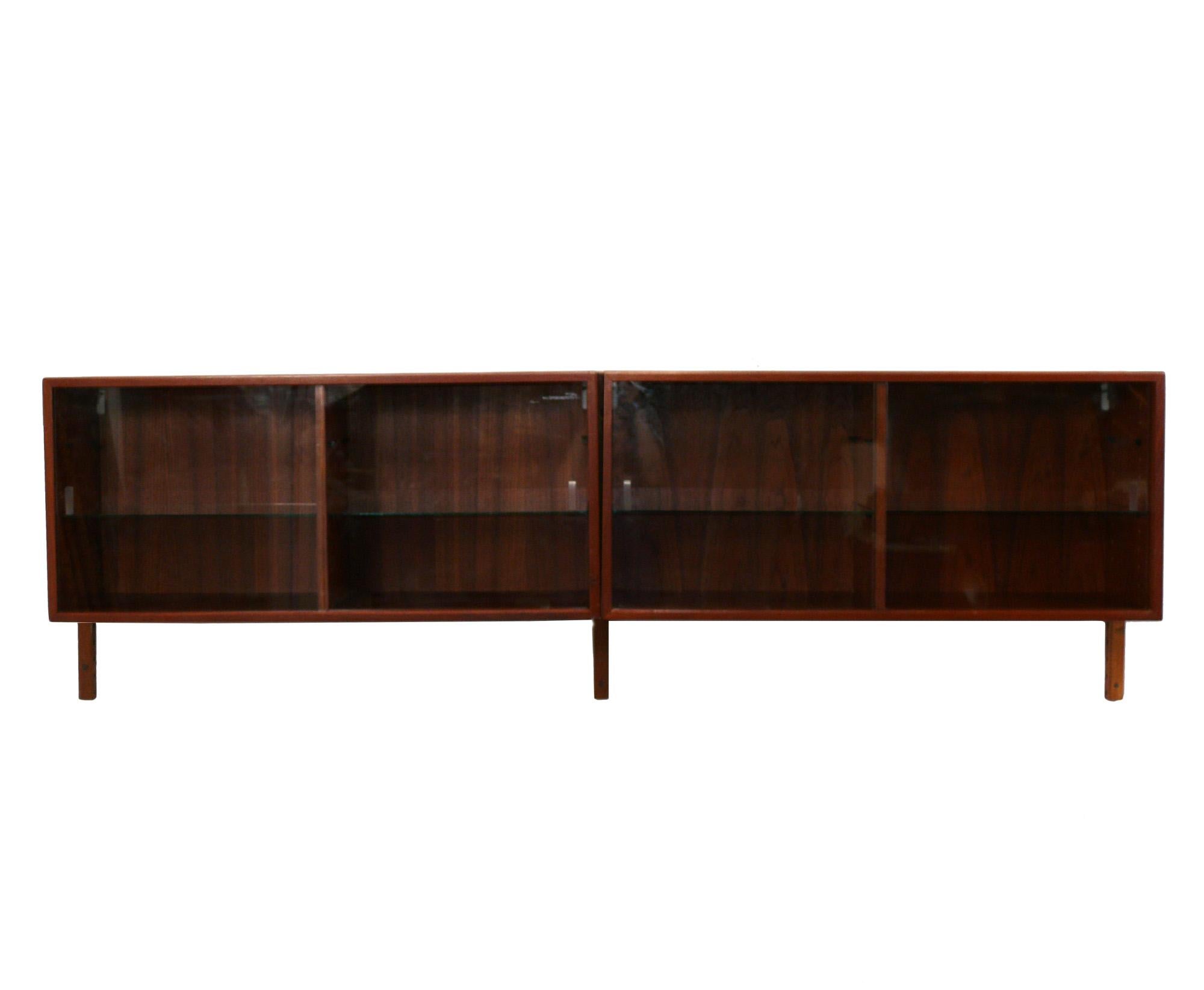 Danish Modern Teak Bookshelf Wall Unit, Denmark, circa 1960s. This piece is a versatile size and can be used as a bookshelf, bar, media cabinet, vitrine, or wall cabinet. It consists of three wall mounted brackets, two cabinets with four sliding