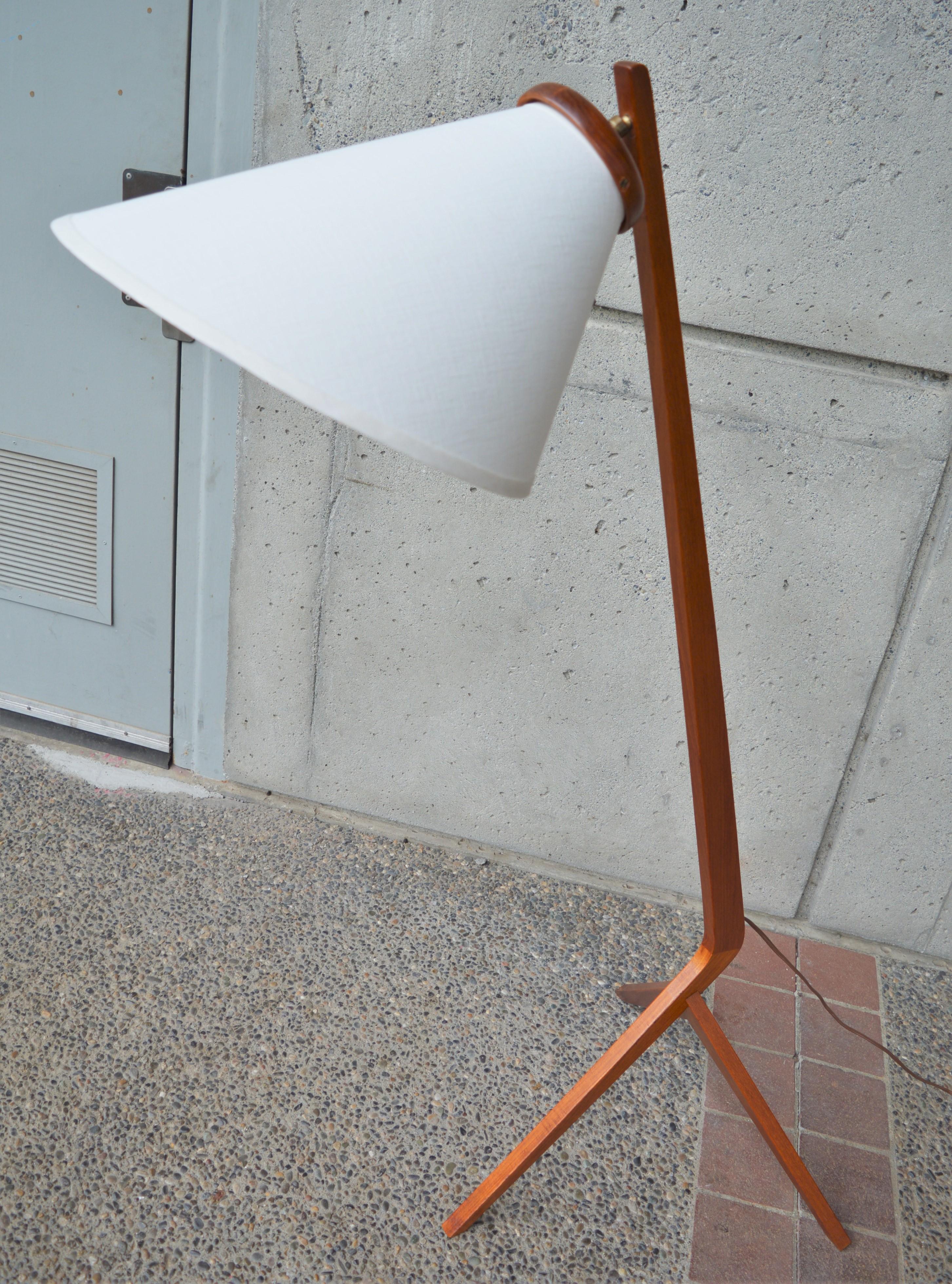 This iconic Danish modern teak Boomerang tripod floor lamp has killer lines and is in excellent condition! Featuring a nice rich patina and brass articulating hardware that holds the lampshade where positioned. Sporting a brand-new custom linen