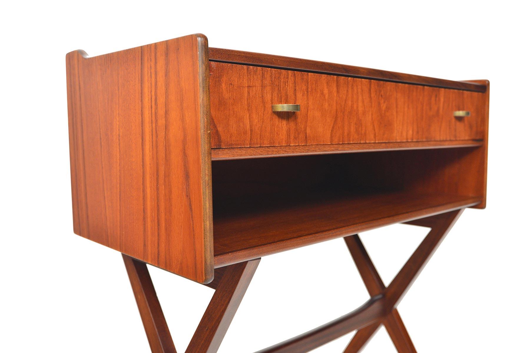 This Danish modern midcentury teak chest offers a stunning form! The chest holds a single drawer with brass half-moon pulls. A raised lip runs the sides. A phenomenal X-form base supports the piece. In excellent original condition.